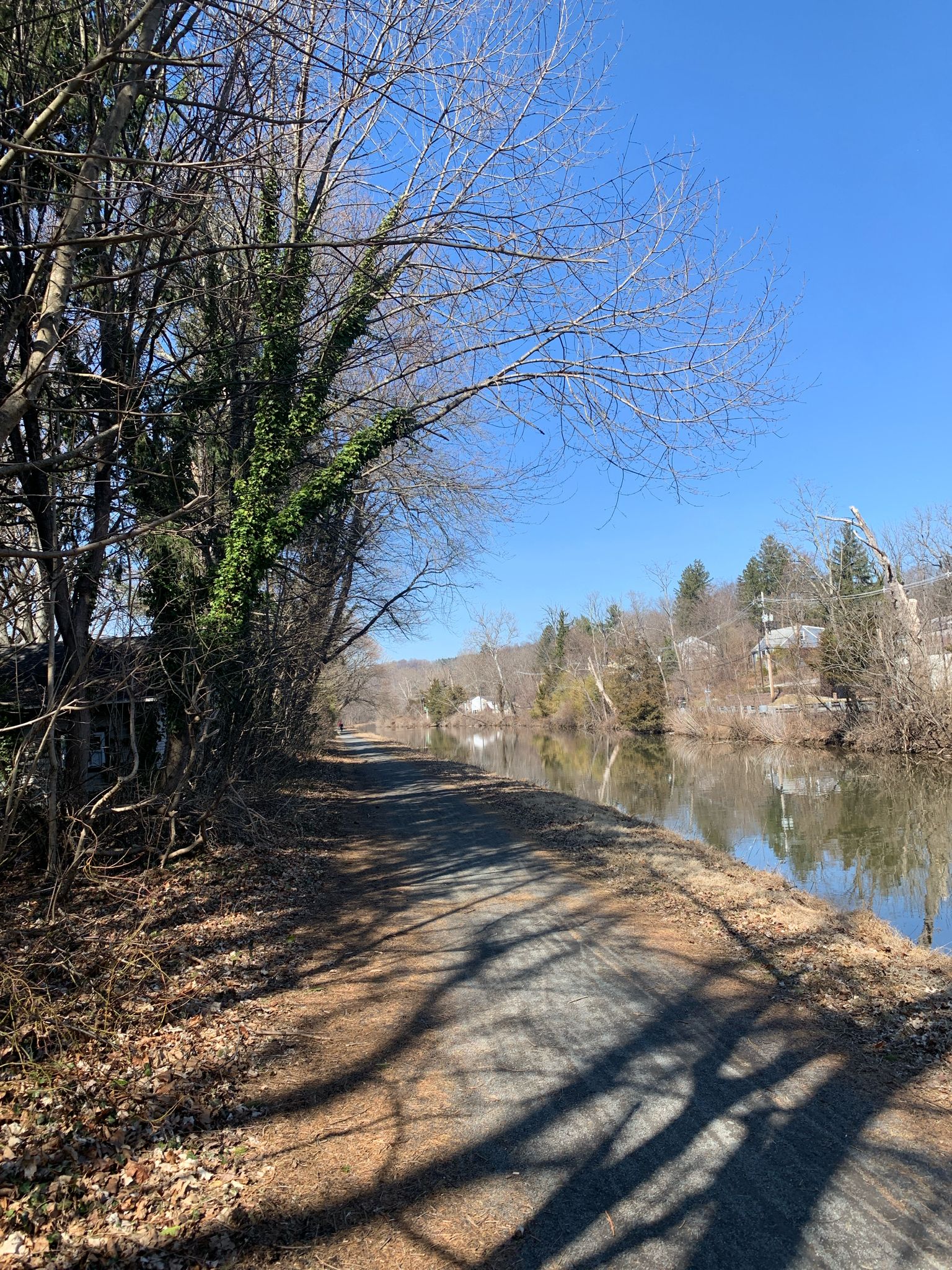 A dirt path runs beside a calm canal under a bright blue sky. - Washington Crossing Bridge – Washington Crossing Bridge loop from Washington Crossing