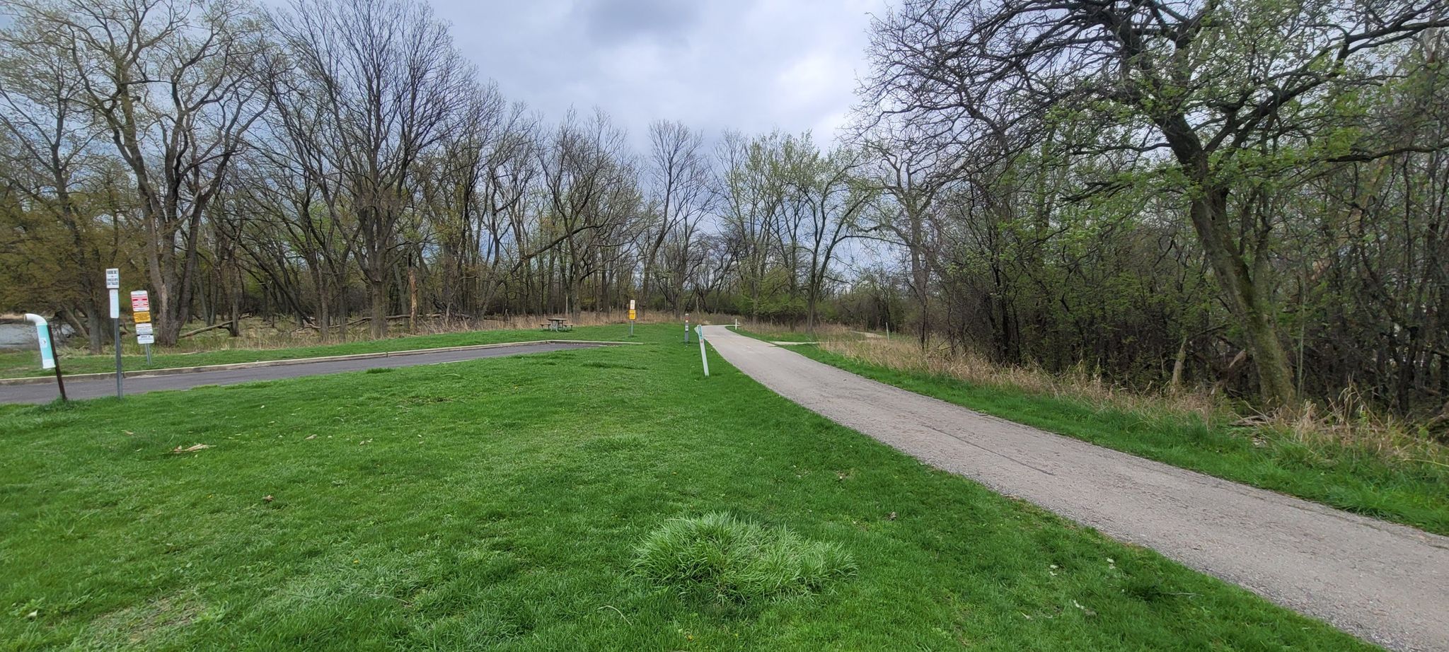 Paved path through green grass and bare trees under an overcast sky. - North Branch Trail: Skokie Lagoons Loop