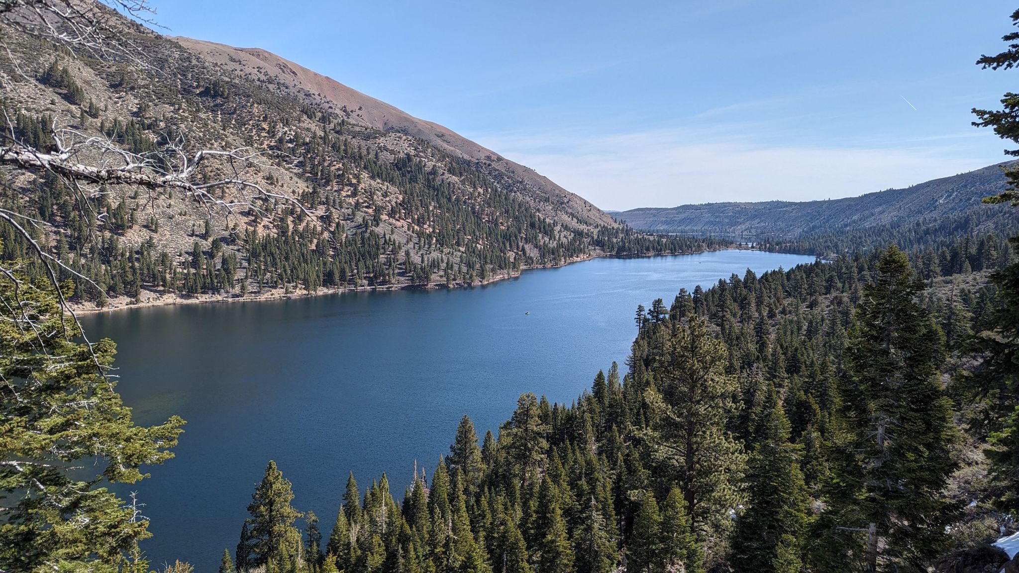 A long blue lake surrounded by forested mountains under a clear sky. - Horse Creek Trail