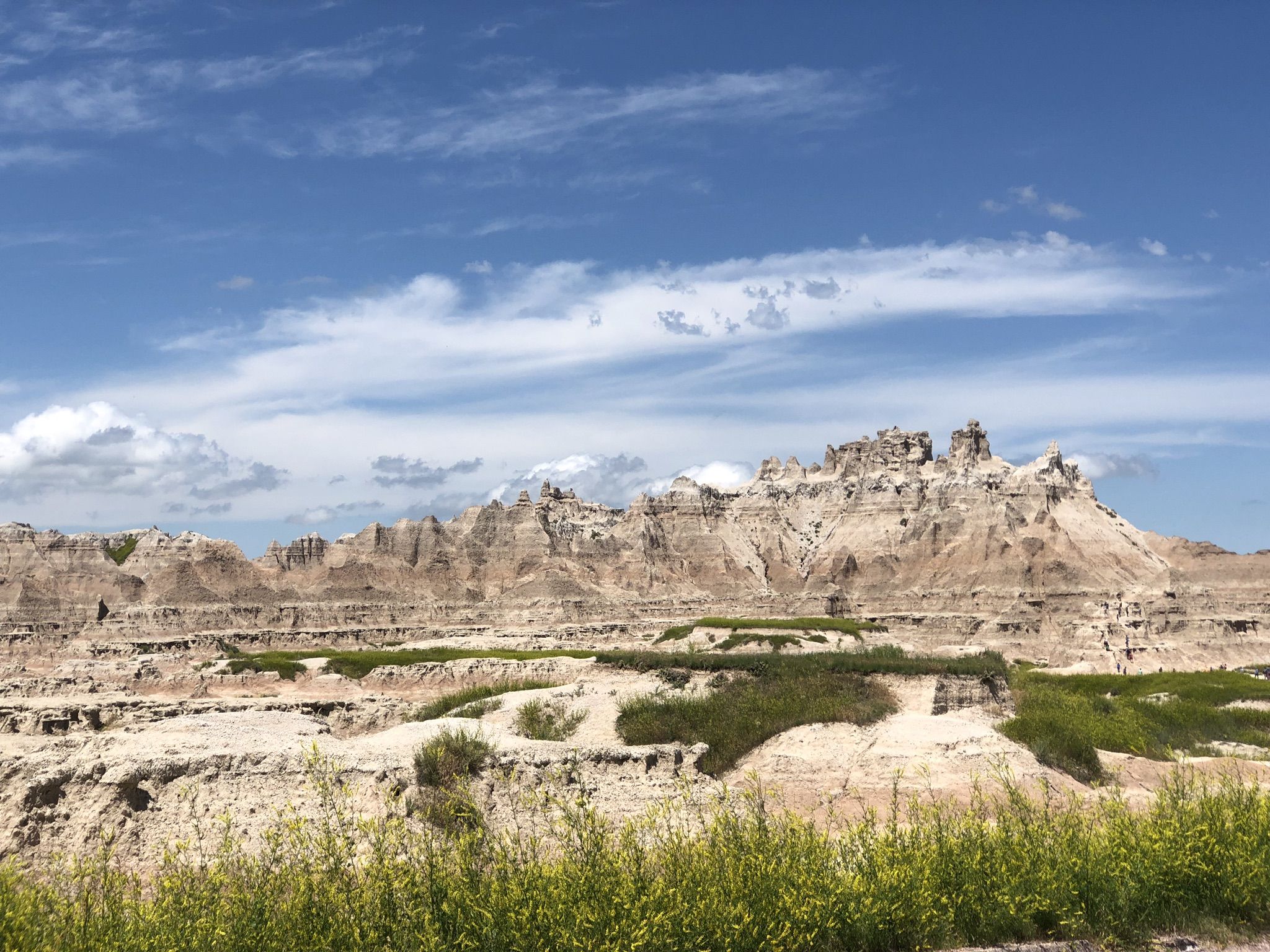 Rocky badlands formations with green shrubs under a partly cloudy sky. - Northeast-Big Foot Loop