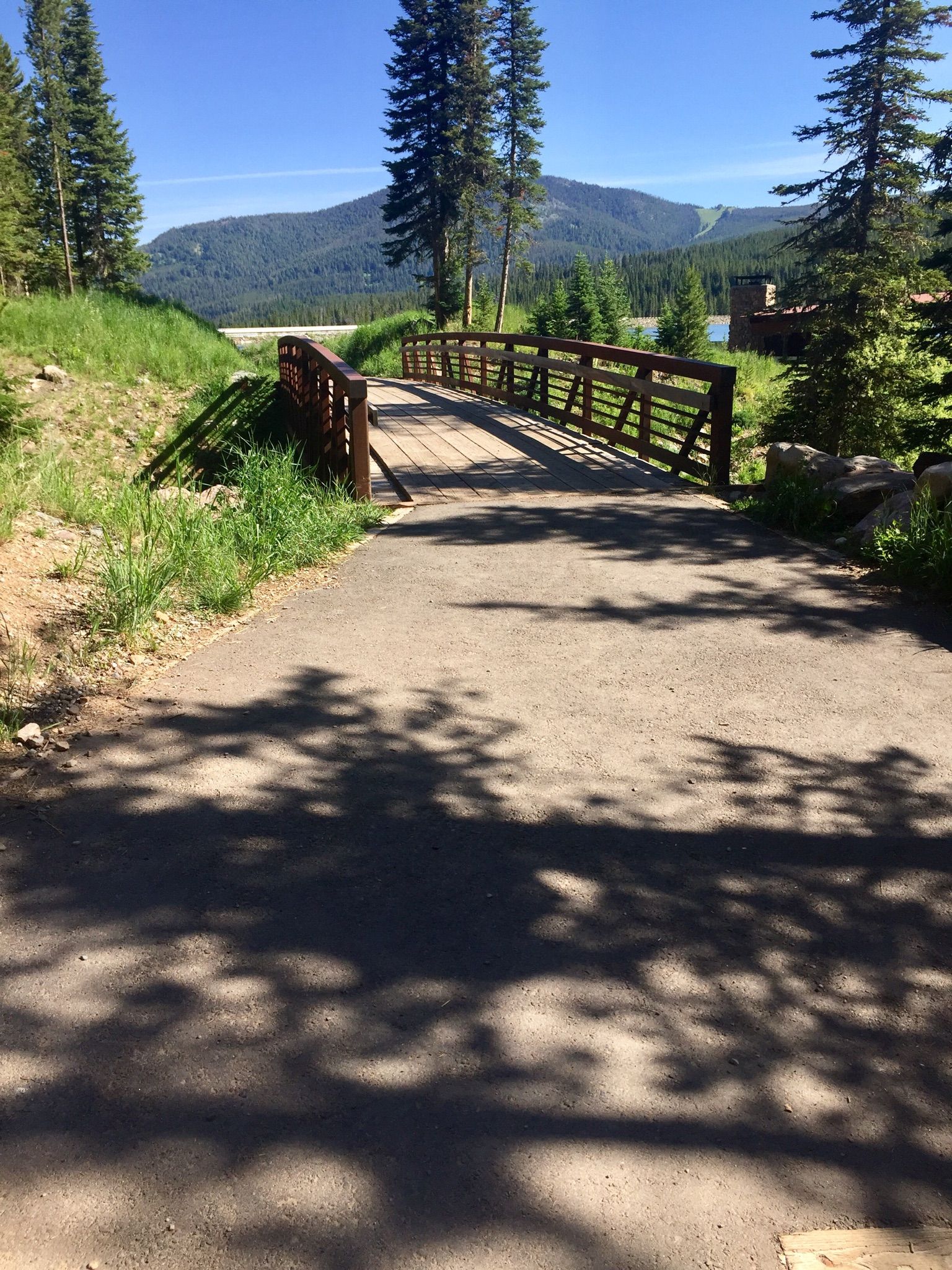 Paved path leading to a wooden bridge on a sunny day. - Hyalite Reservoir – Hyalite Reservoir loop from Middle Creek Dam