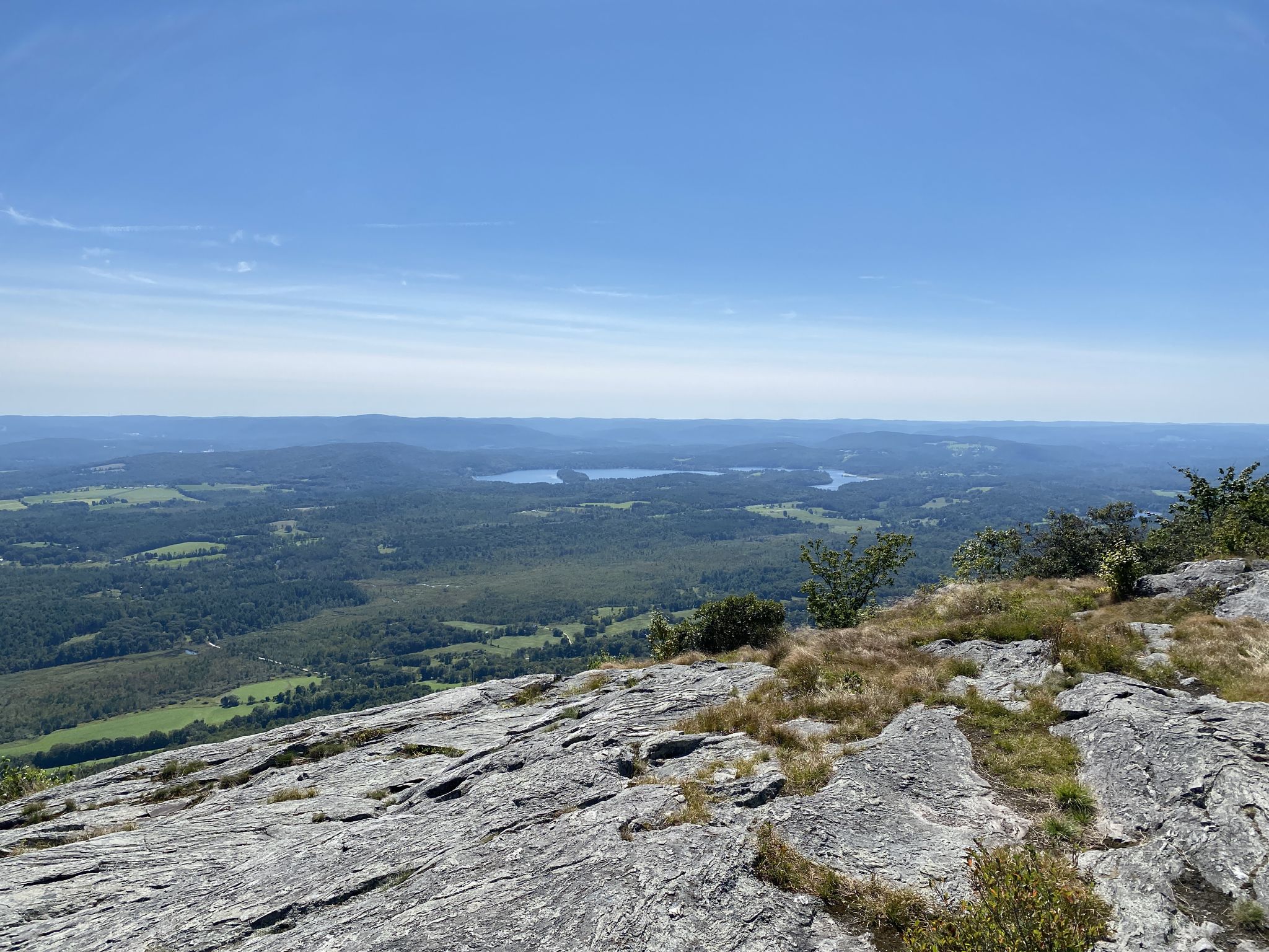 Expansive view from a rocky mountain top with distant lakes and forests. - Nordwest Road and Racebrook Trail - Mount Washington State Forest