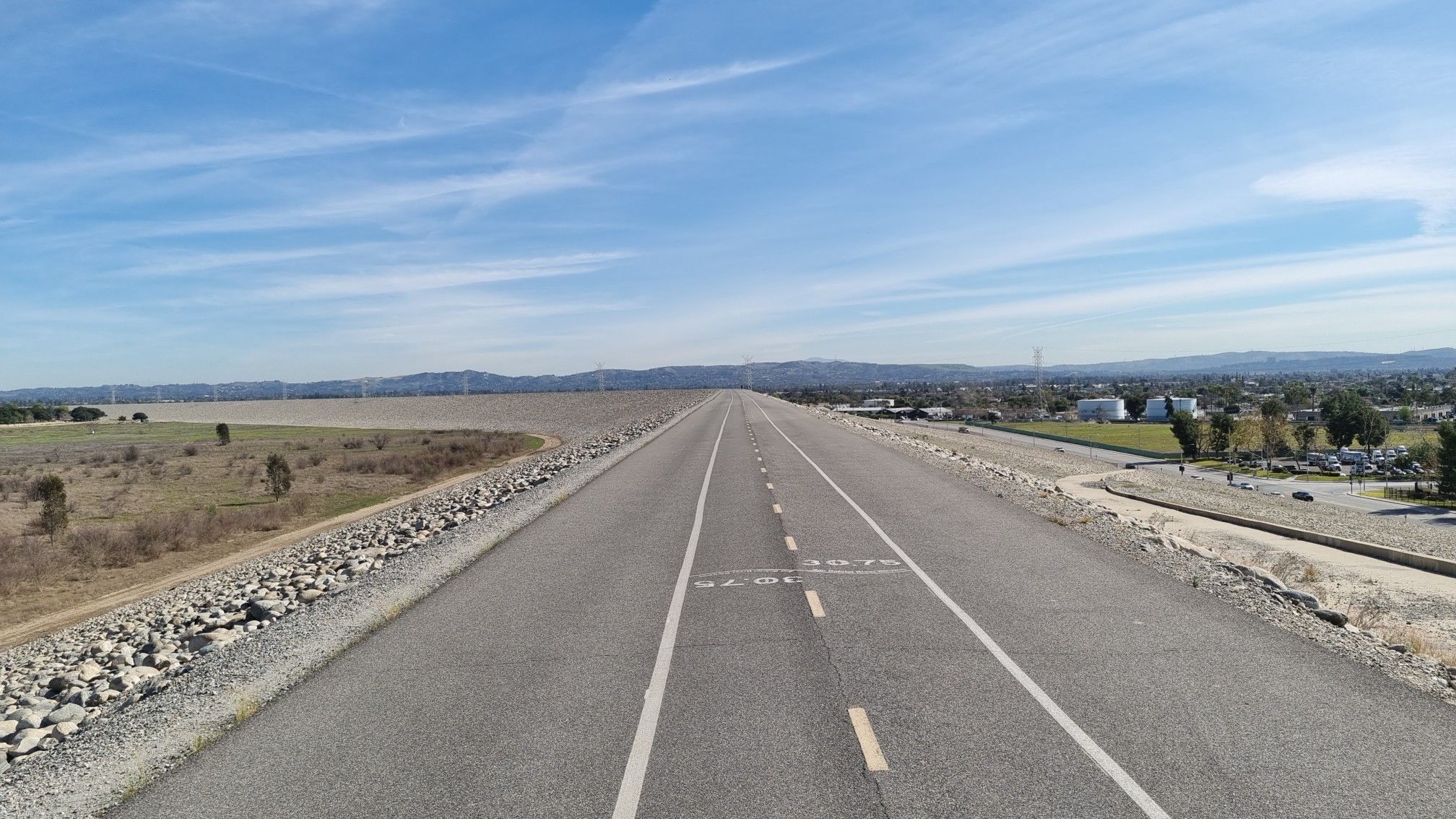 A long, straight paved road stretches into the distance under a clear sky. - Santa Fe Flood Control Basin – Bosque del Rio Hondo loop from El Monte
