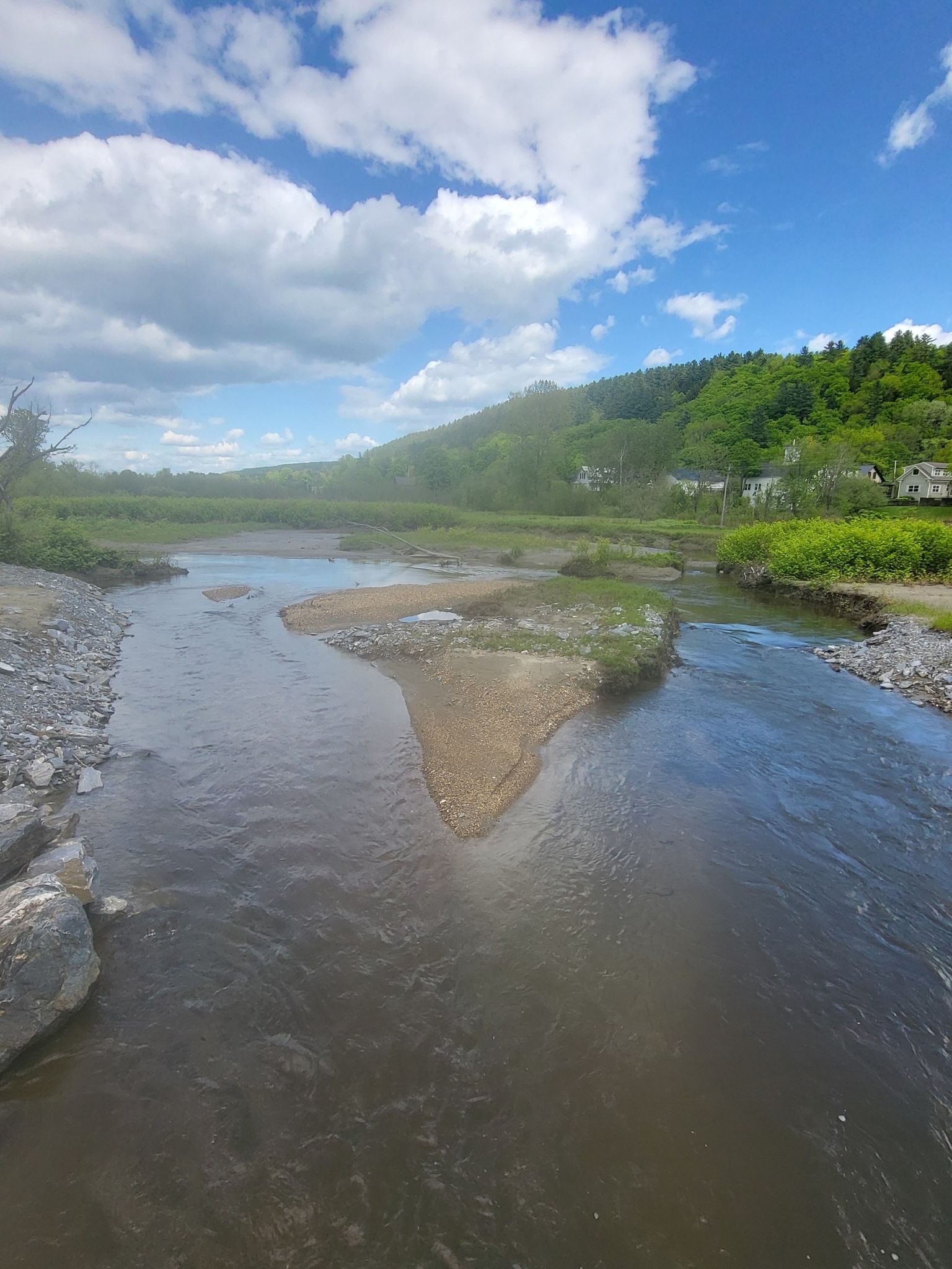 Wide river with a sandbar, green hills, and houses under blue sky. - Grist Mill Bridge – Morgan Covered Bridge loop from Giddings Cemetery