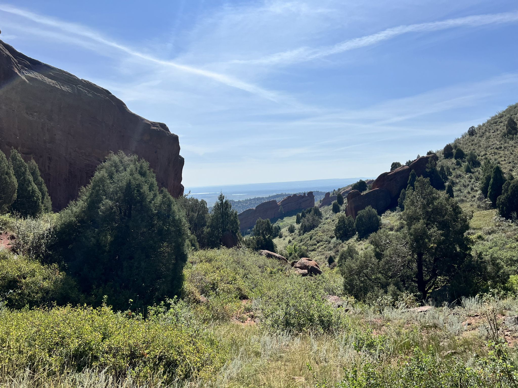 Sunny valley with green trees, large rock formations, and a blue sky. - Bear Creek/Dakota Ridge loop
