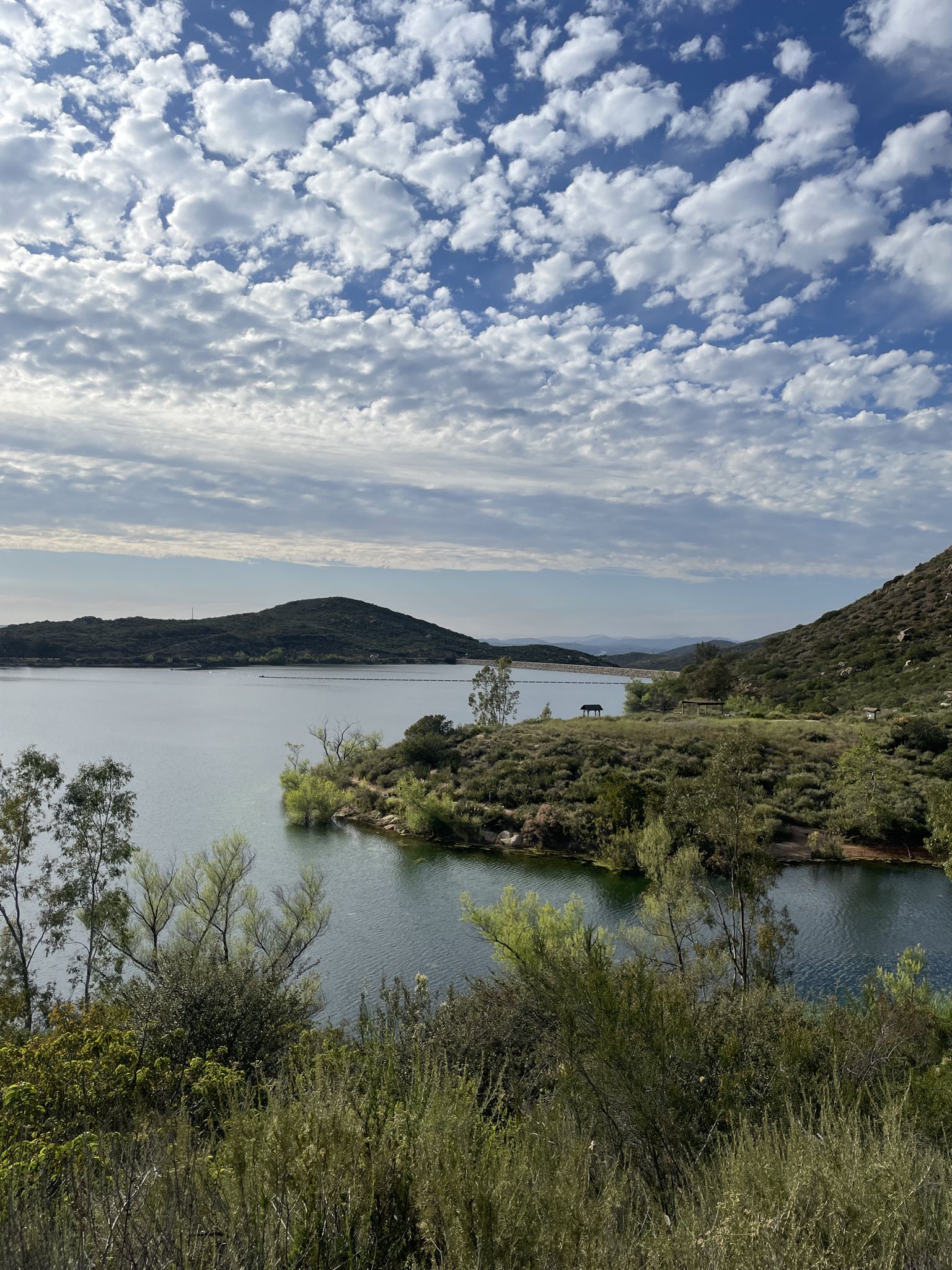 Serene lake with small islands and distant mountains under a partly cloudy sky. - Lake Poway – Lake Poway loop from Poway High School