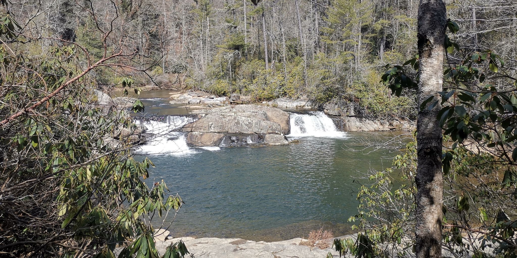 River with multiple small waterfalls and rocky banks, surrounded by trees. - Erwin's View Trail