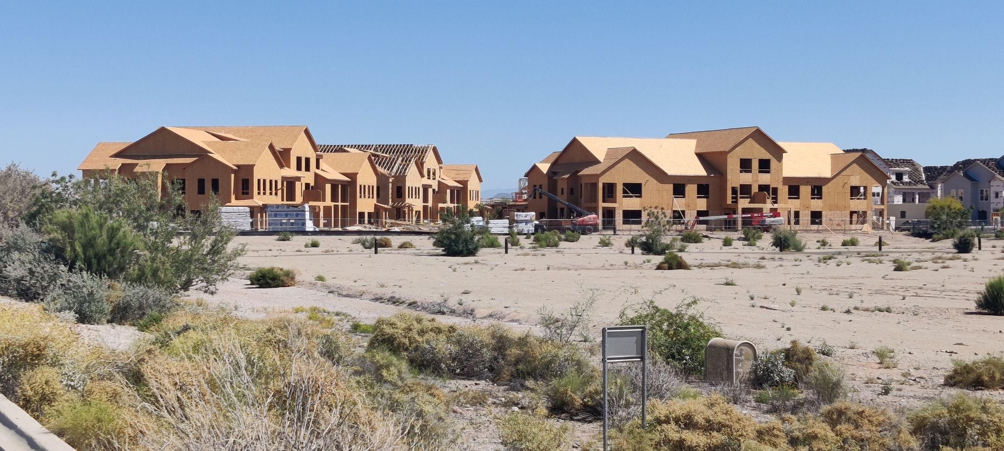 New residential buildings under construction in a dry, open landscape under clear sky. - Rio Vista Community Park loop from State Farm Stadium
