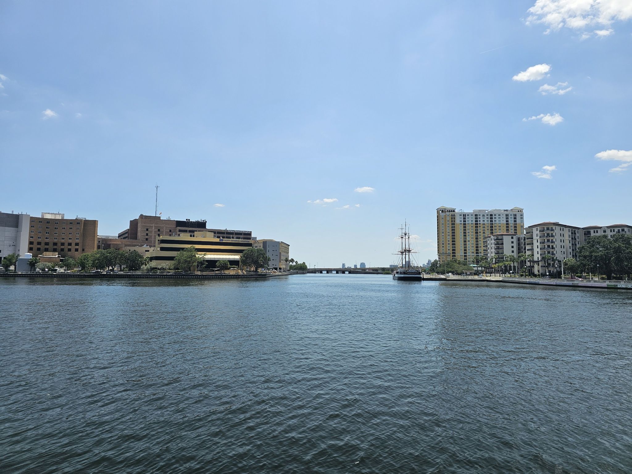 Wide river with urban buildings and a tall ship under a clear sky. - Tampa Cruise Port – Selmon Greenway loop from Hyde Park
