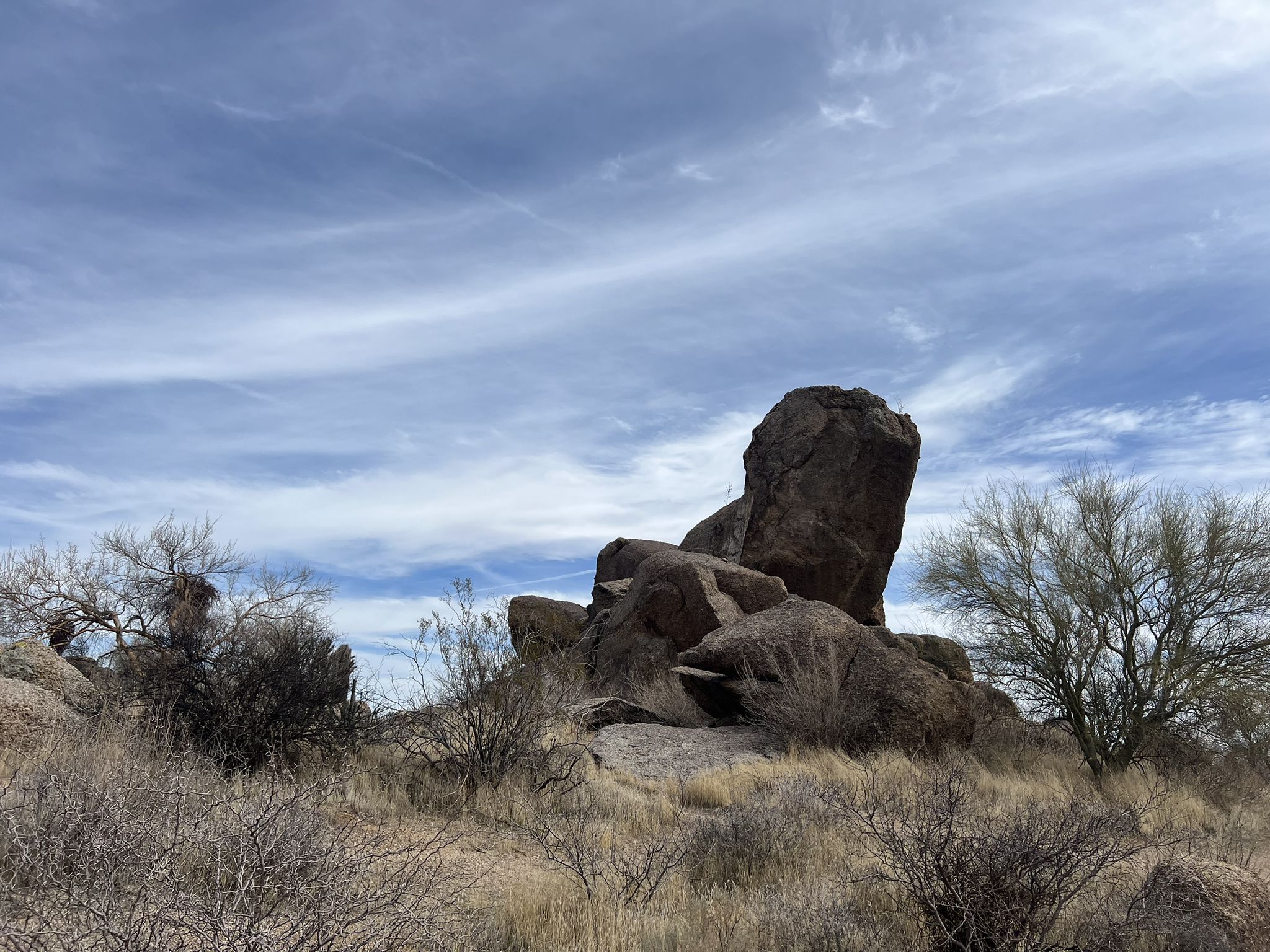 Massive dark rock formations dominate a dry desert landscape under cloudy sky. - View of Tonto National Forest loop from Maricopa Trail Trailhead at Granite Mountain