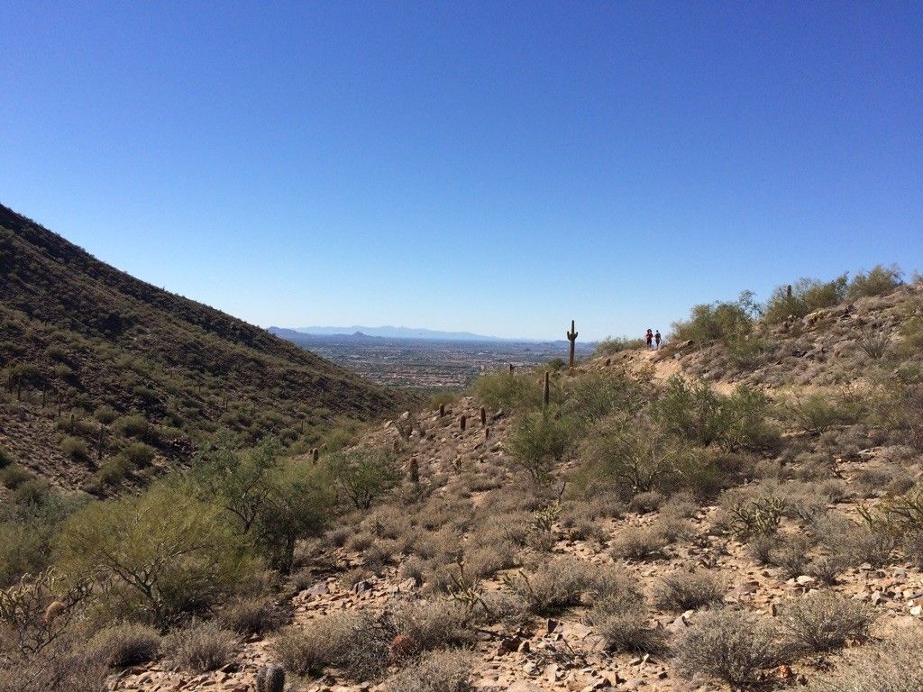 Hikers on a desert trail overlooking a vast valley on a clear day. - Gateway Trail