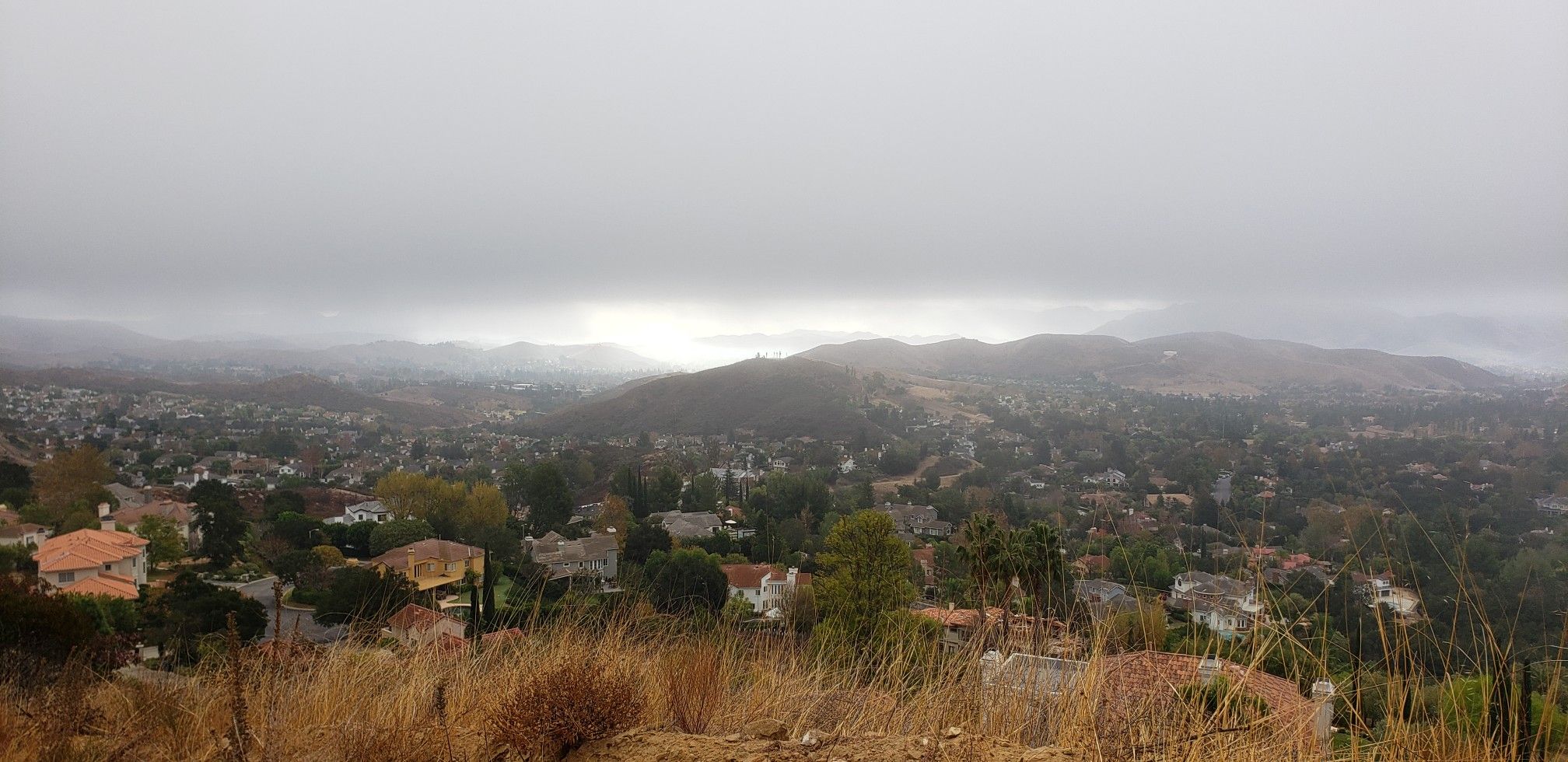 Panoramic view of a town nestled in hills under a cloudy, overcast sky. - Simi Peak and China Flat Loop