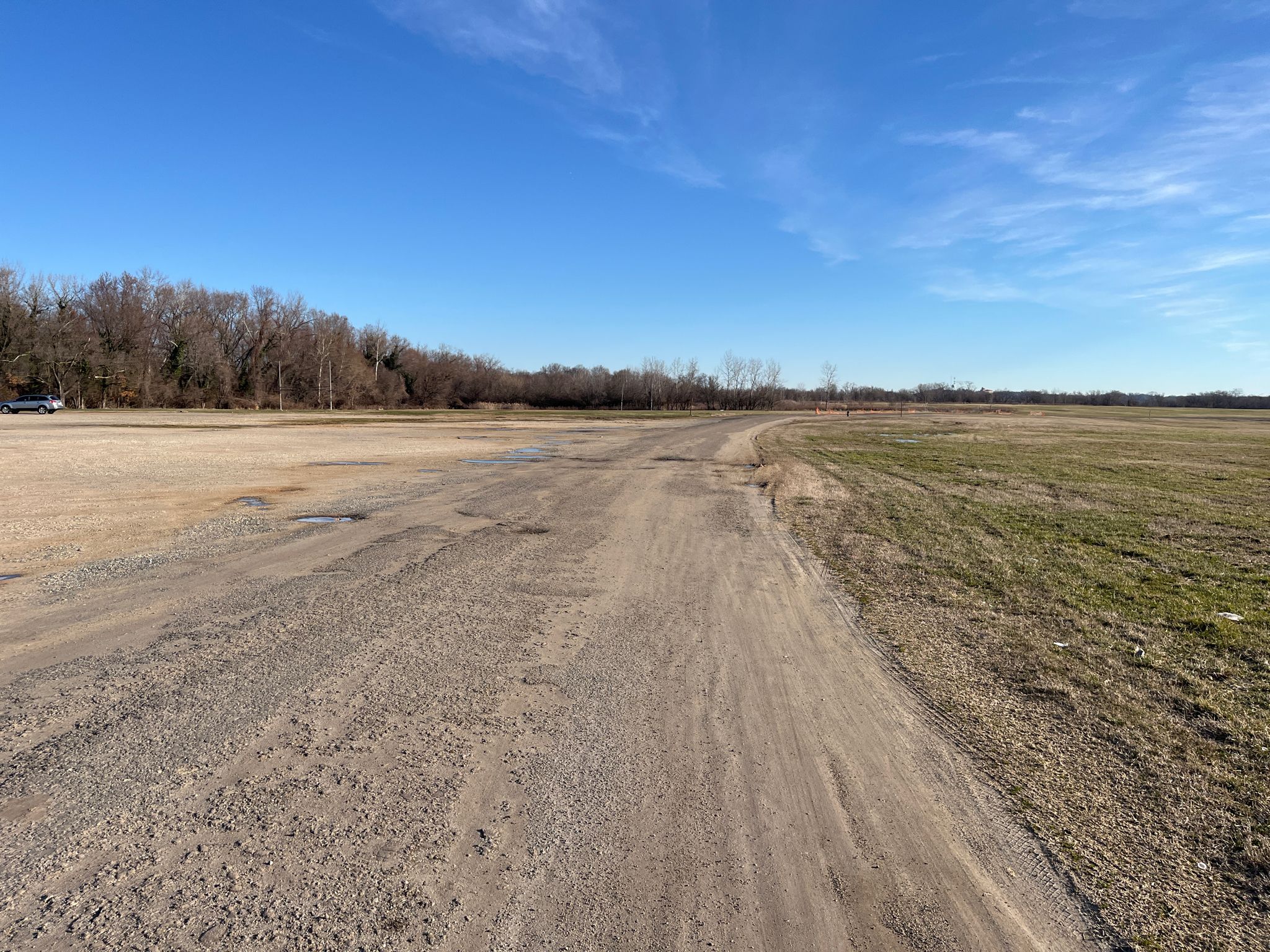 Wide dirt path through open fields under a clear blue sky. - Anacostia Riverwalk Trail