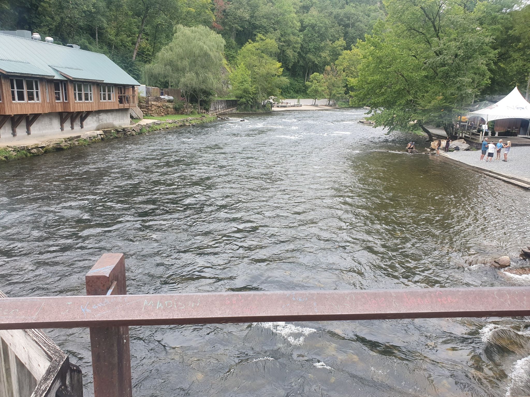 Wide river with a large wooden building and people on the far bank. - Nantahala River Gorge Whitewater Rafting Paddle Route