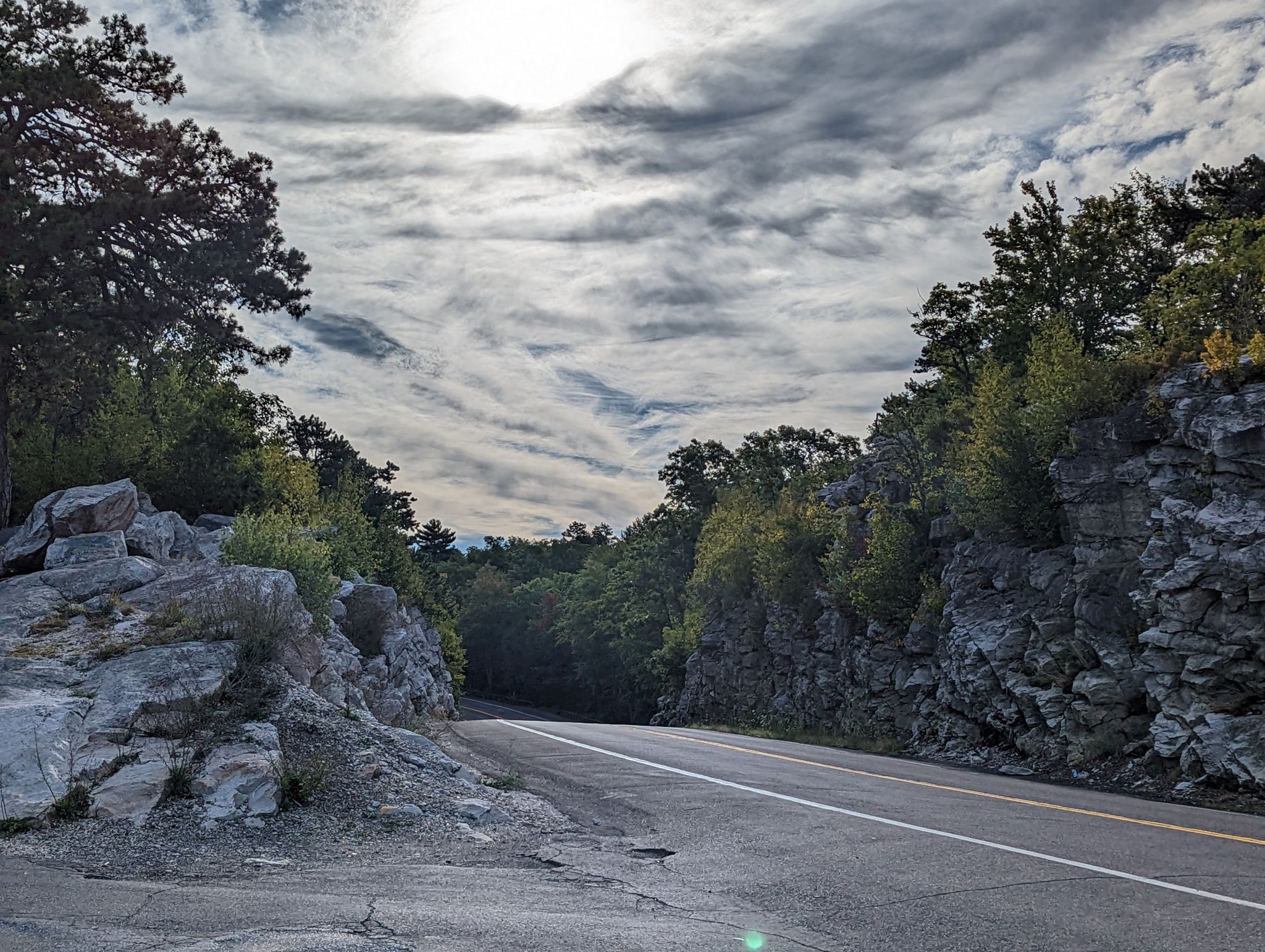 An empty road cuts through a forested, rocky landscape under an overcast sky. - Gardiner to Minnewaska State Park Preserve loop