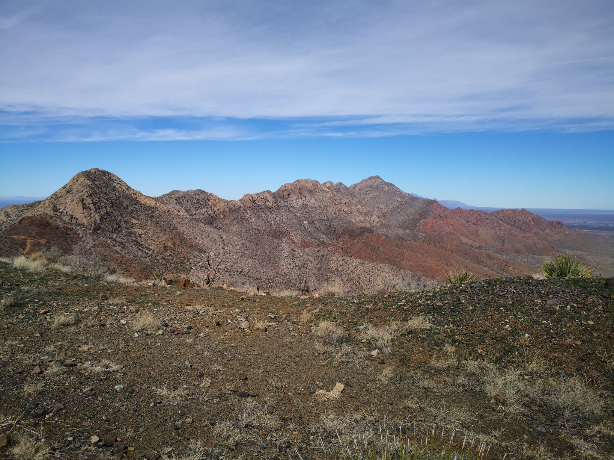 Expansive desert mountain range with varied colors under a bright blue sky. - North Franklin Peak Trail