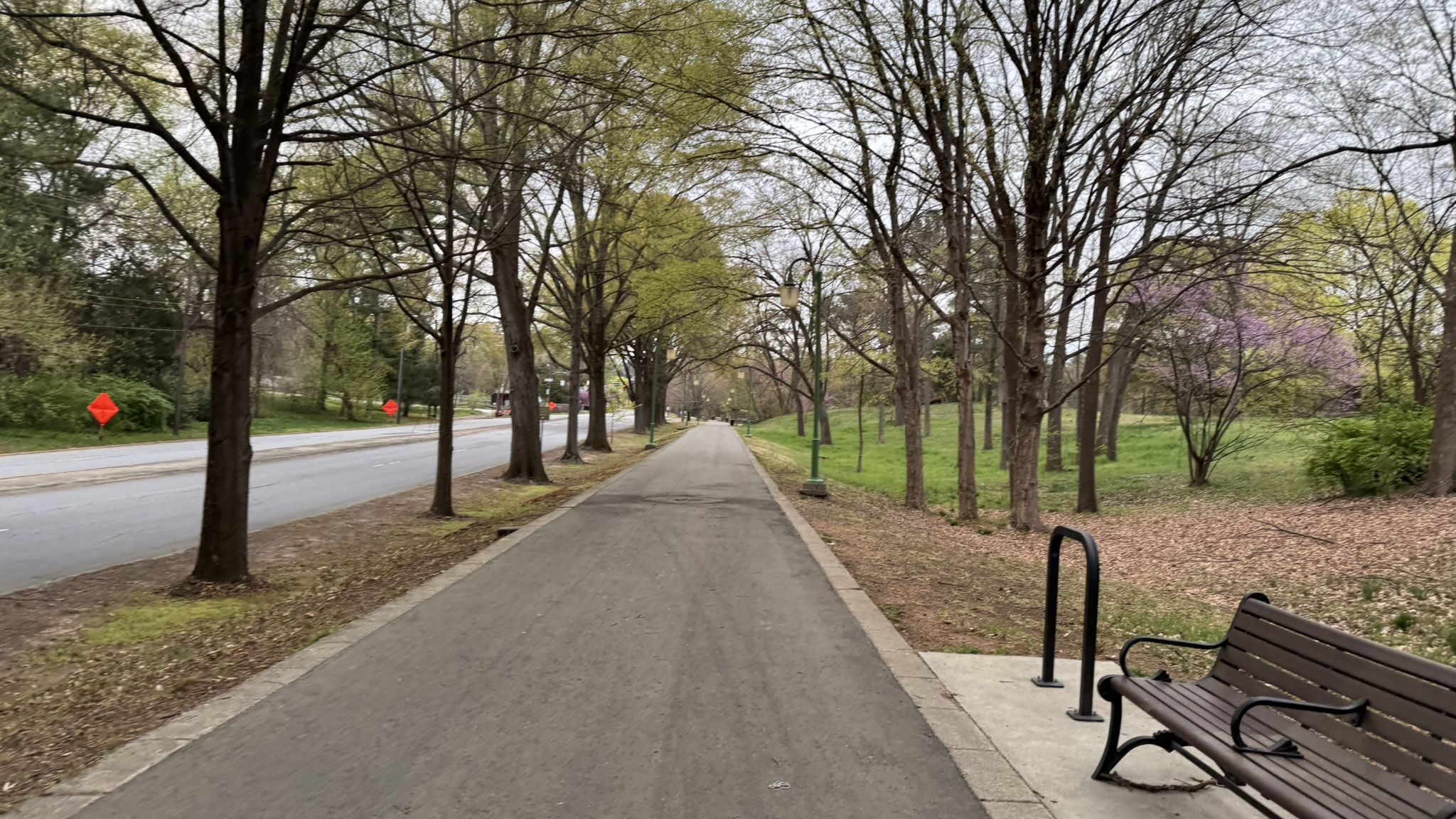 A paved path runs alongside a road and trees under an overcast sky. - Strollway – Long Branch Trail loop from Winston-Salem
