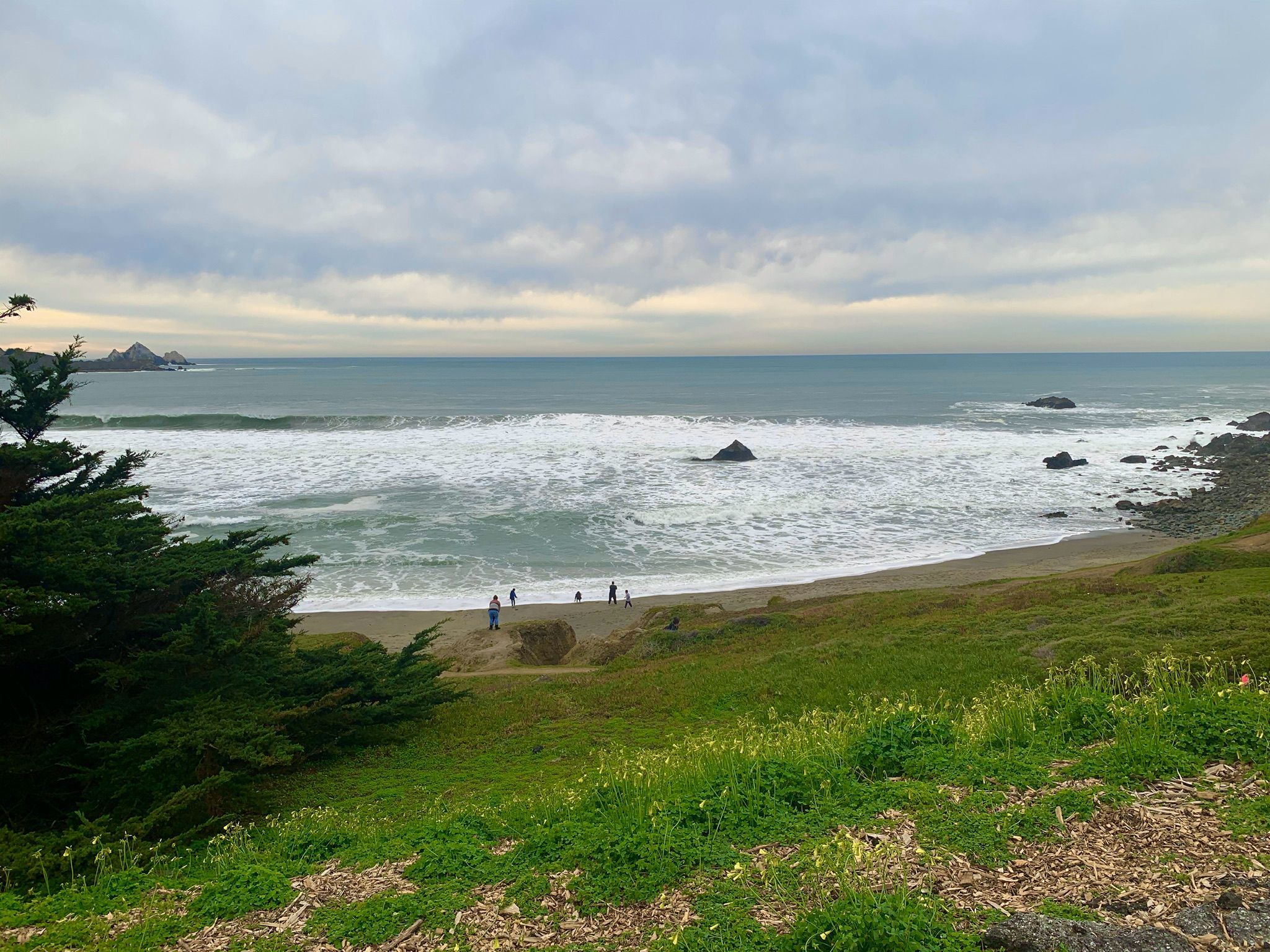 Overcast ocean view with waves, a sandy beach, and people enjoying the shore. - Pacifica State Beach – Pacifica Beach Overlook loop from Pacifica