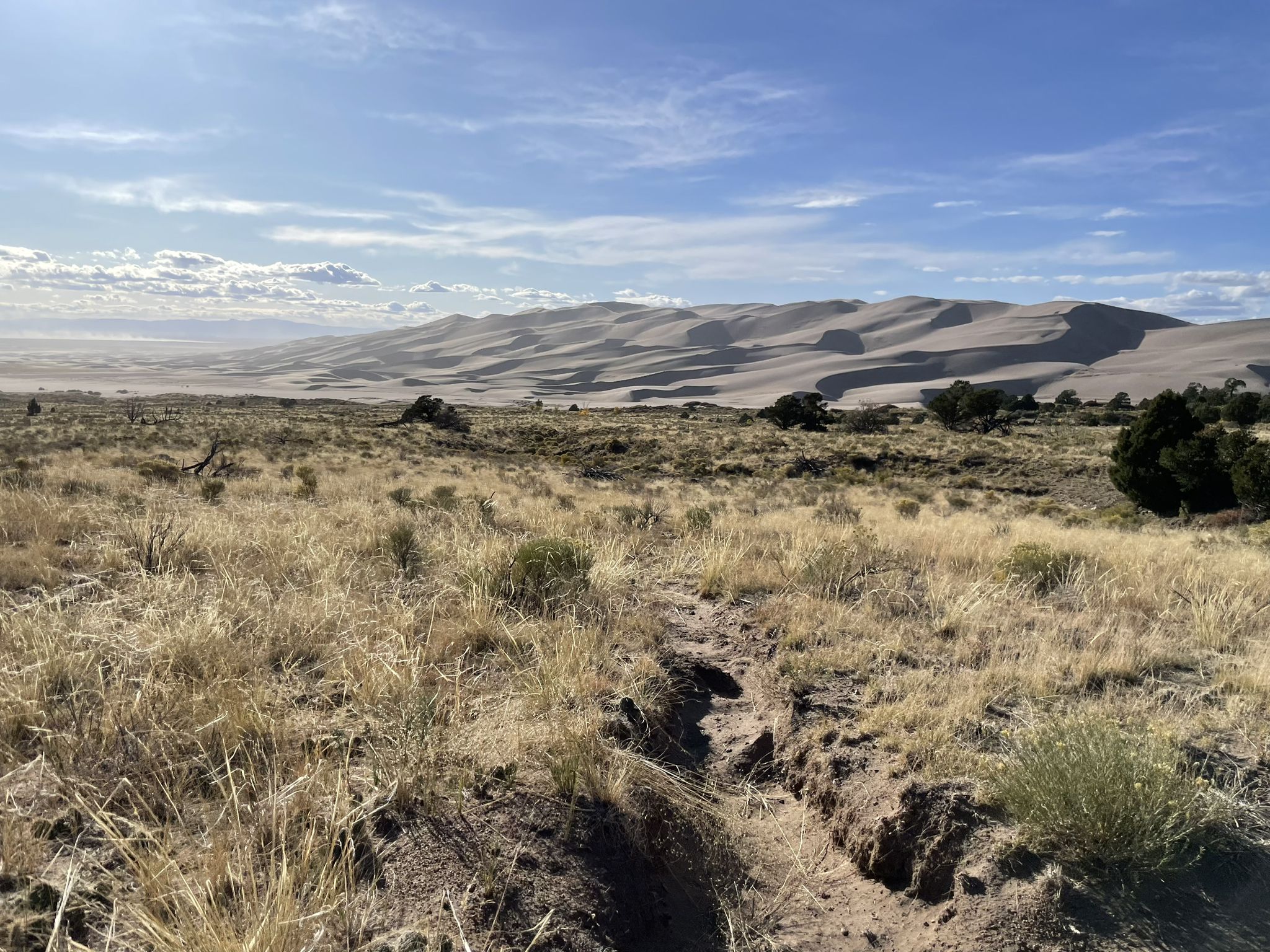 Desert landscape with large sand dunes under a partly cloudy sky. - Dunes Overlook Trail