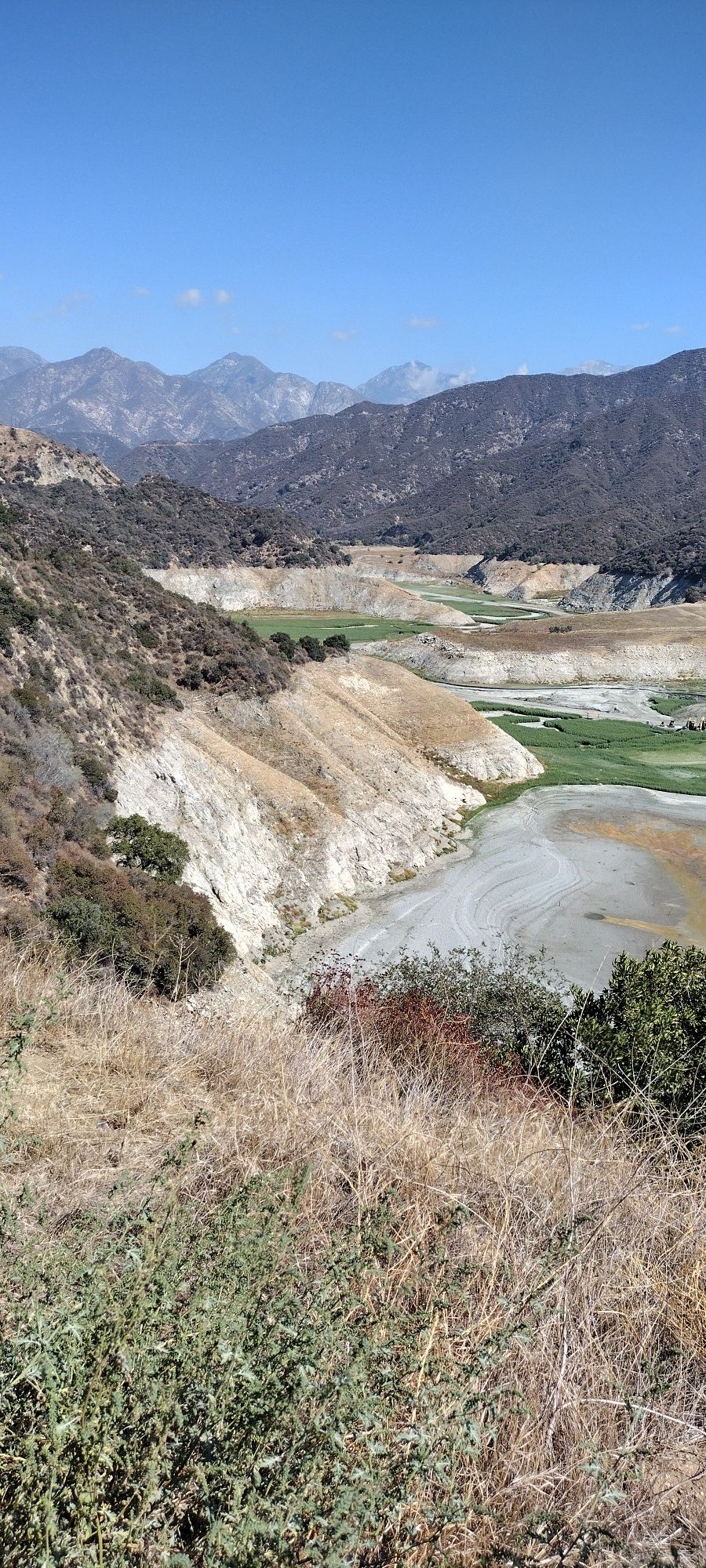Arid mountain landscape with a dry riverbed and distant peaks under clear sky. - San Gabriel Canyon Road & Mt Baldy loop from Lario Staging Area