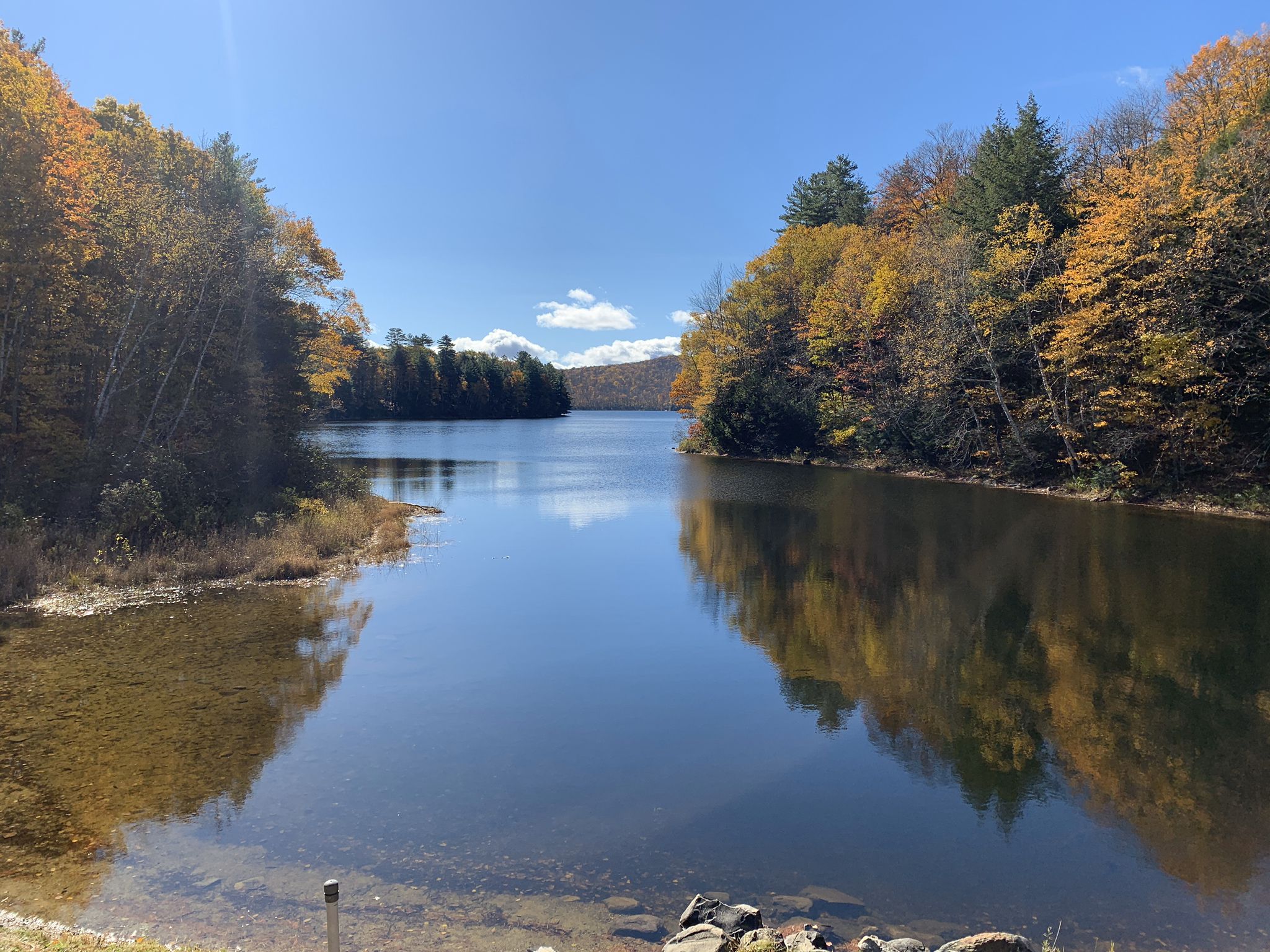 Calm lake reflecting autumn trees under a bright blue sky. - Silver Lake Loop Trail