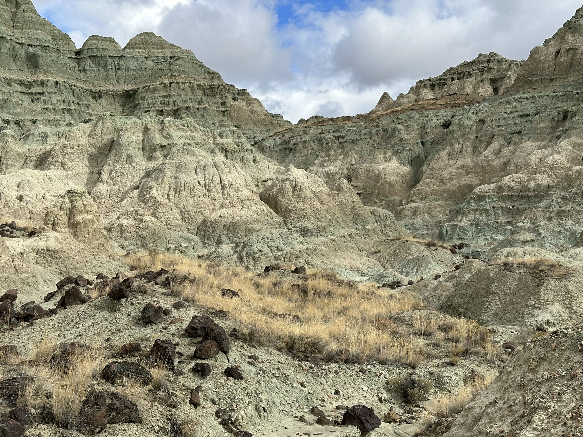 Arid valley with layered rock formations, dry grass, and scattered rocks. - Island in Time Trail