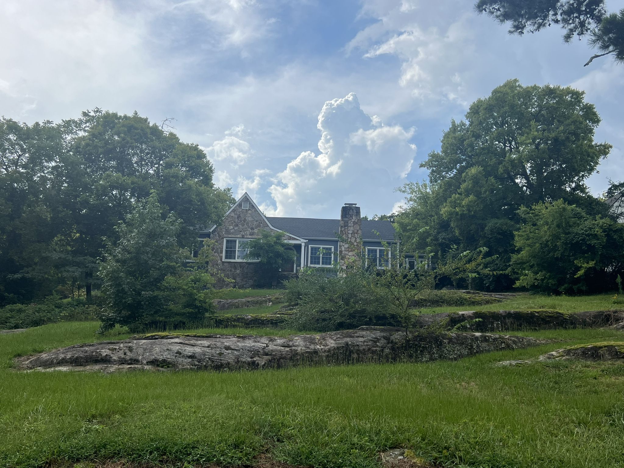 Stone house surrounded by green trees and grass under a cloudy sky. - Chattanooga loop via Cameron Hill