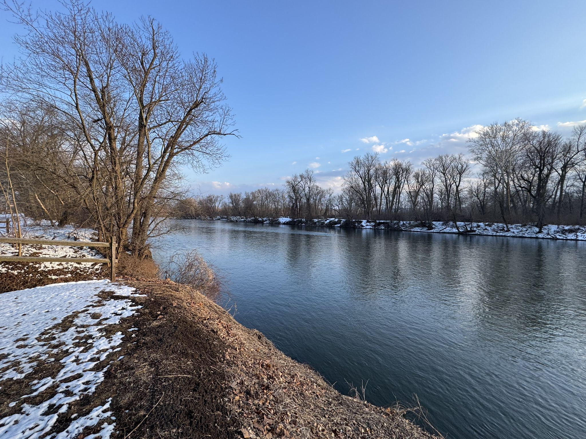 Wide river with snowy banks and bare trees under a bright winter sky. - Lower Perkiomen Valley Park loop from Audubon