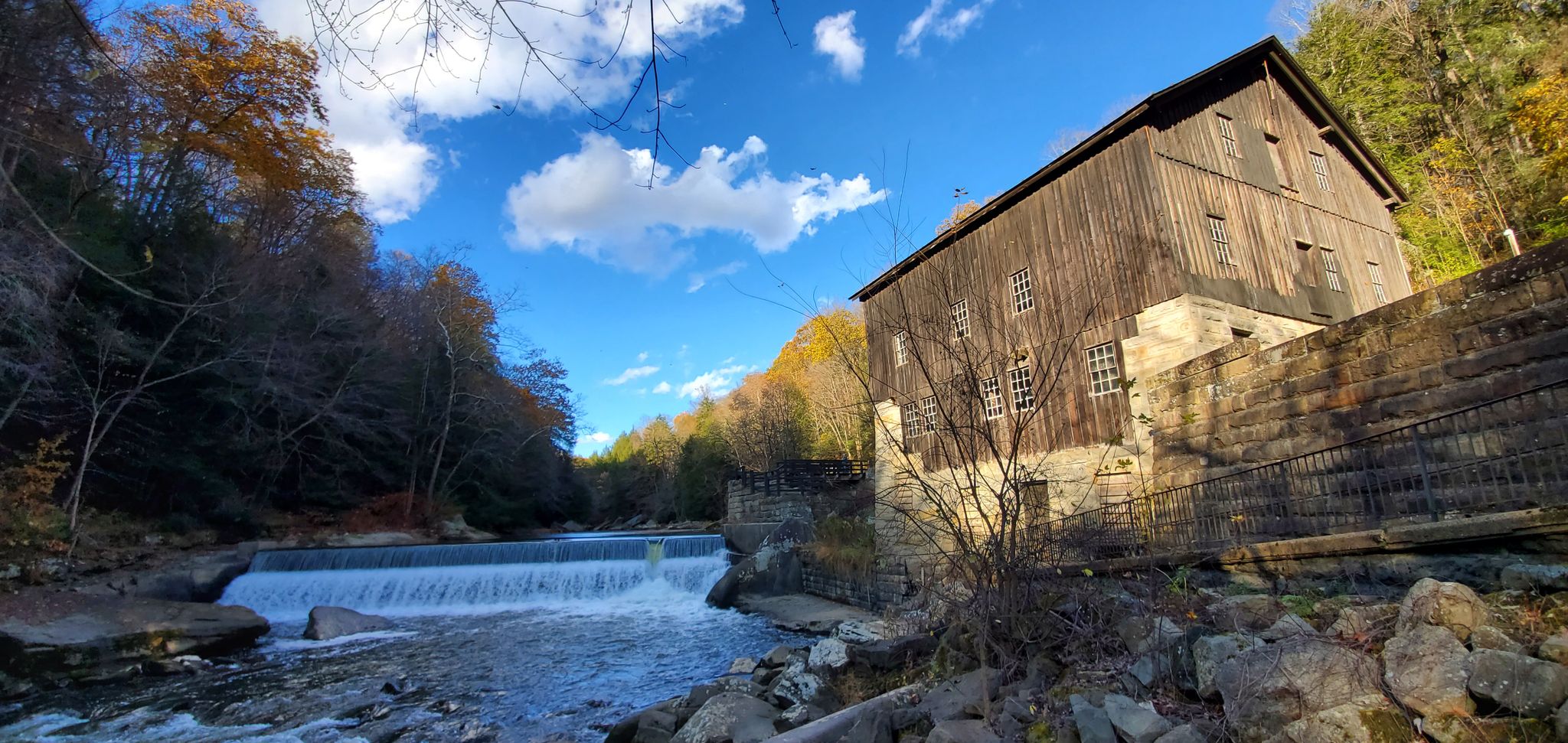 An old wooden mill building stands by a river with a waterfall. - Connoquenessing Creek – McConnells Mill State Park loop from Route 528 (Evans City) Park & Ride