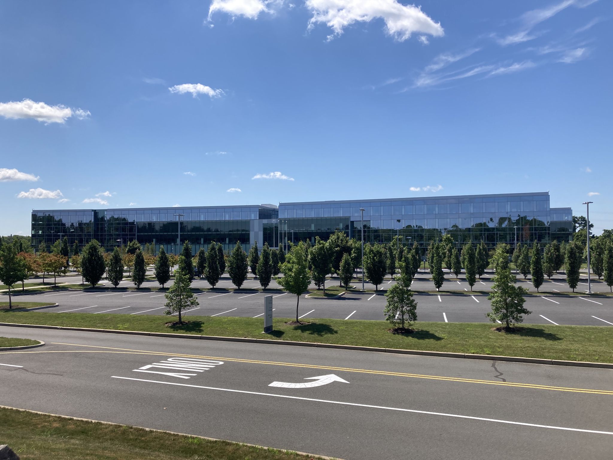 Modern glass building, large parking lot, and trees under a sunny sky. - Hopewell – Lawrence Hopewell Trail loop from Rider University