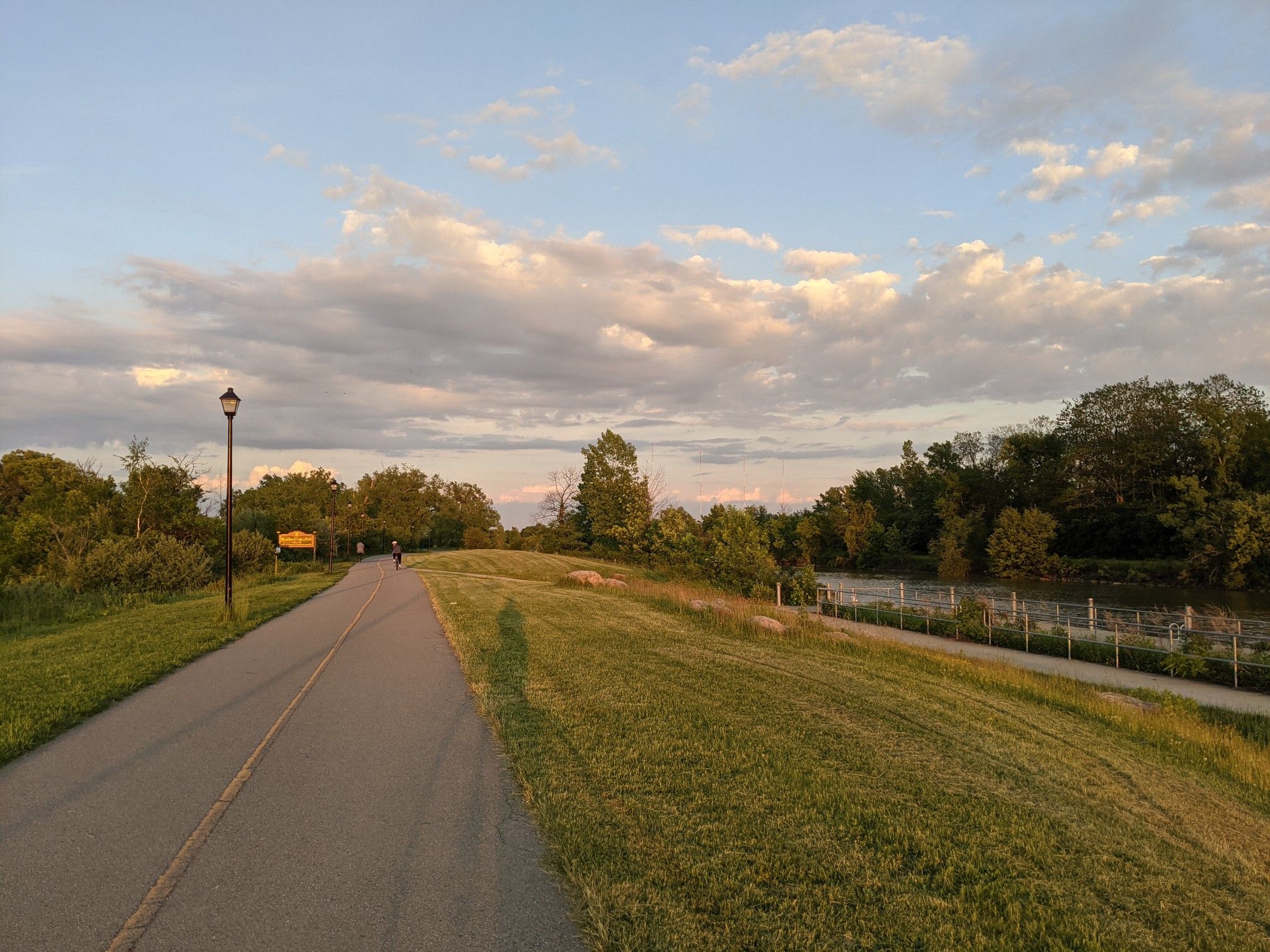 Paved path on a grassy embankment under a cloudy sunset sky. - Running loop from Locust Hill Country Club