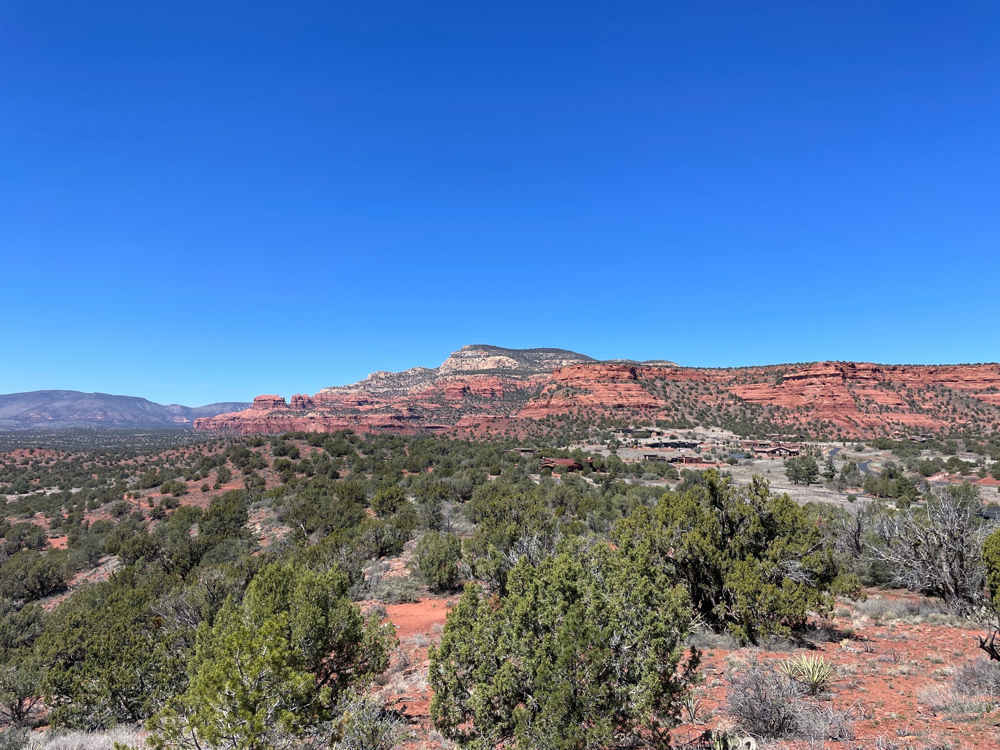 Vast desert landscape with red rock formations, green brush, under clear blue sky. - Girdner and Outer Limits Loop