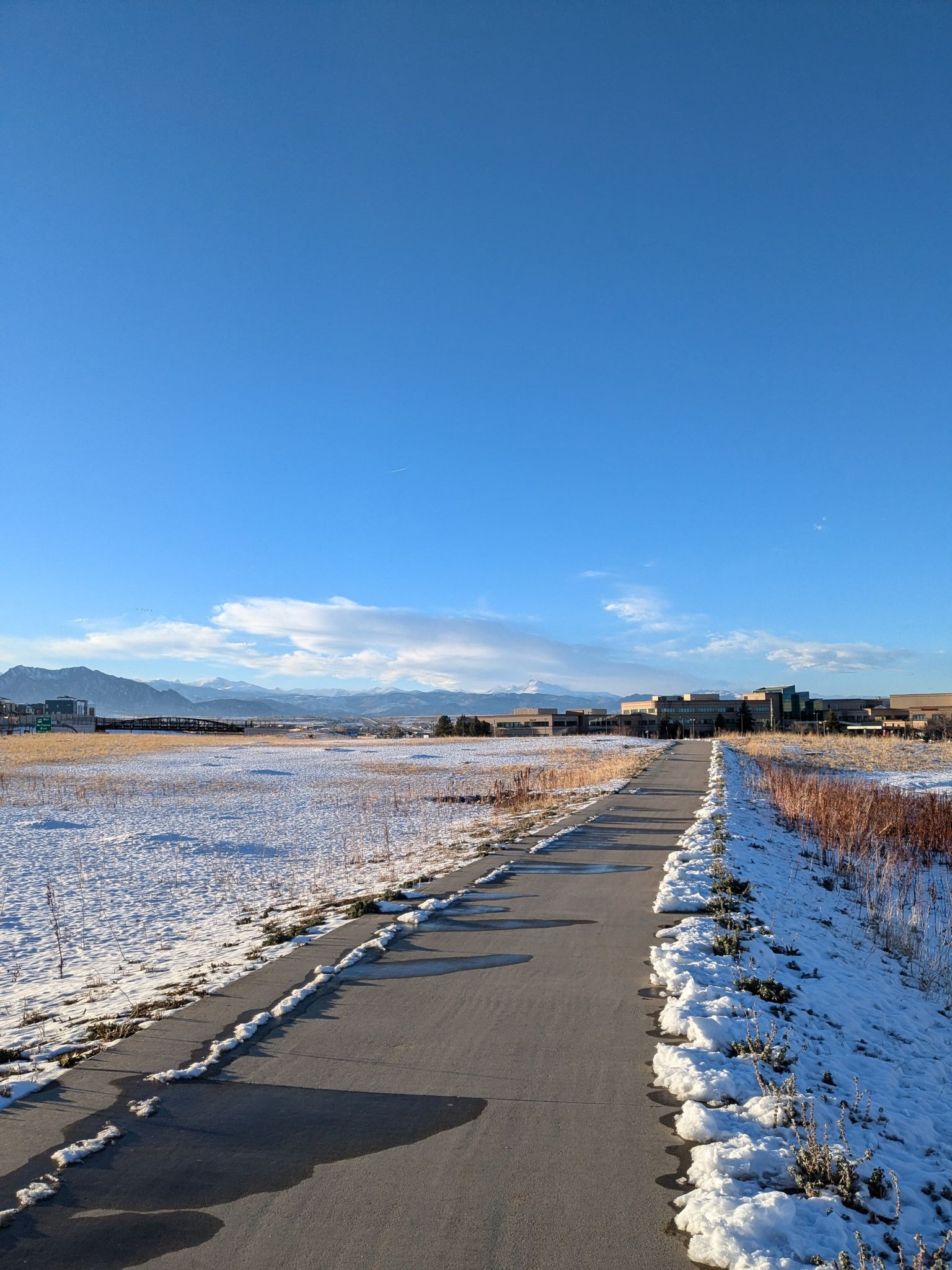 Paved path through snow-covered fields, with distant buildings under a clear sky. - Walnut Creek Open Space – Davidson Mesa Overlook loop from Lac Amora Open Space