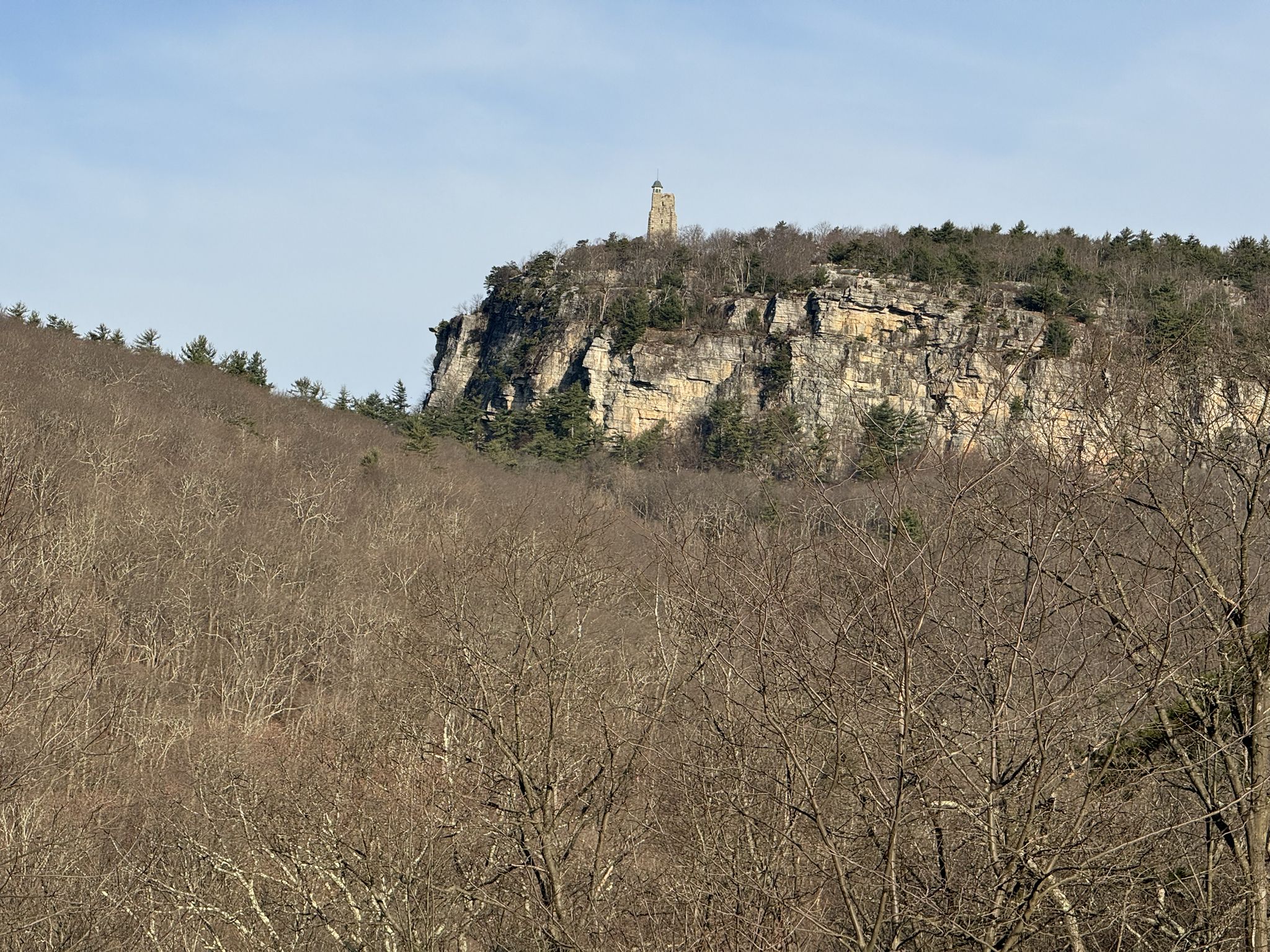 A tall stone tower atop a rocky cliff overlooking bare winter trees. - Duck Pond loop from Mohonk Preserve (Foothills)