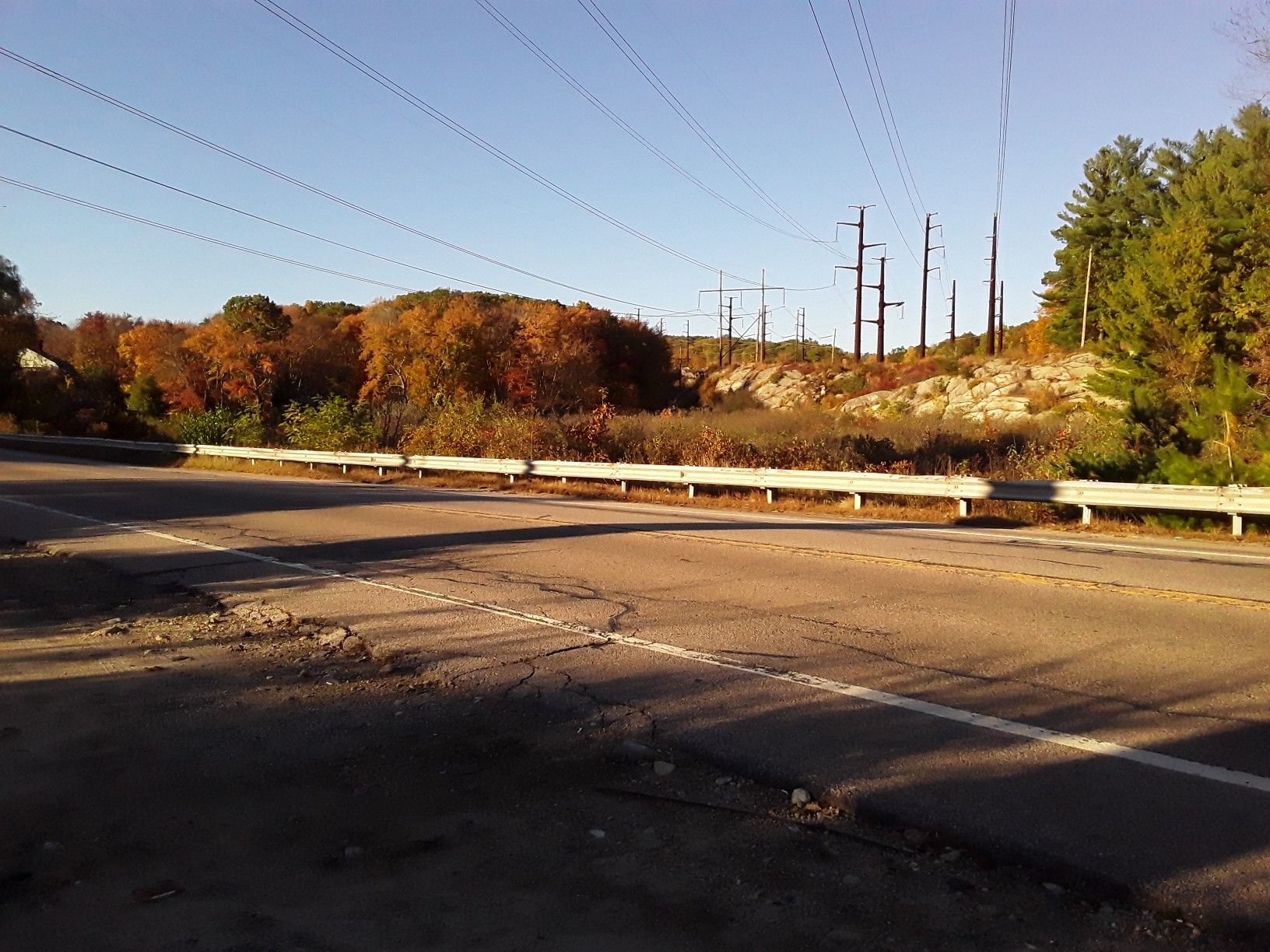 Roadside with power lines, autumn trees, and guardrail under bright sun. - Rhode Island Loop