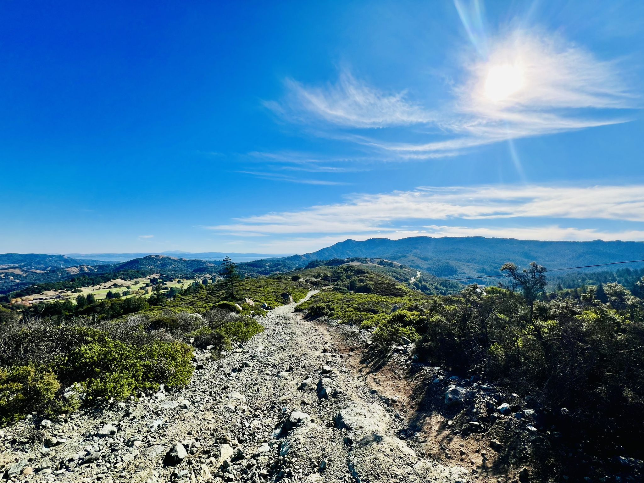 Rocky dirt trail winding through sun-drenched hills under a bright blue sky. - Carson Falls and Pine Mountain Trail