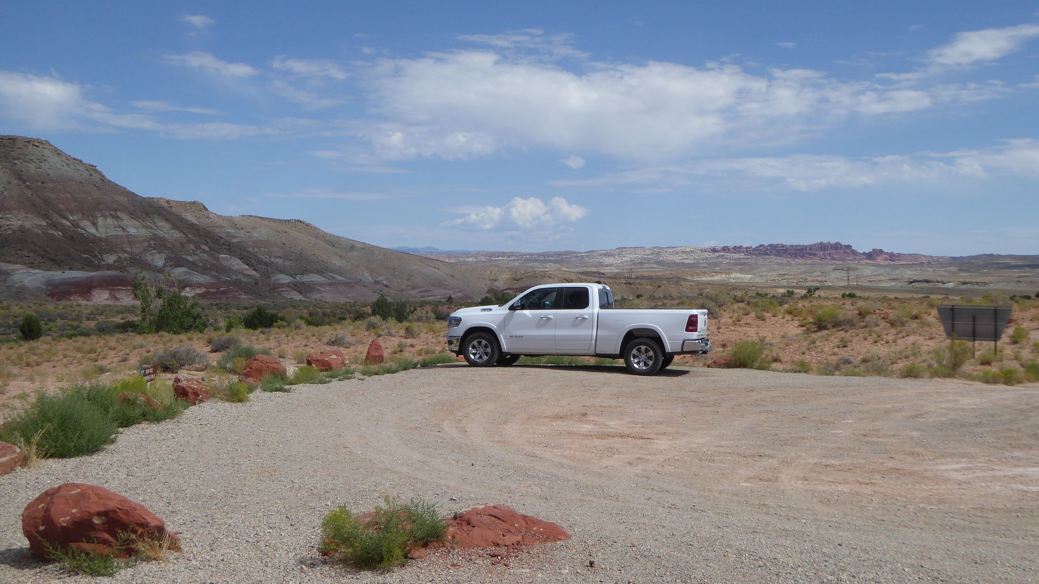 White pickup truck parked on a dirt road in a vast arid landscape. - Mill Canyon Dinosaur Bone Trail