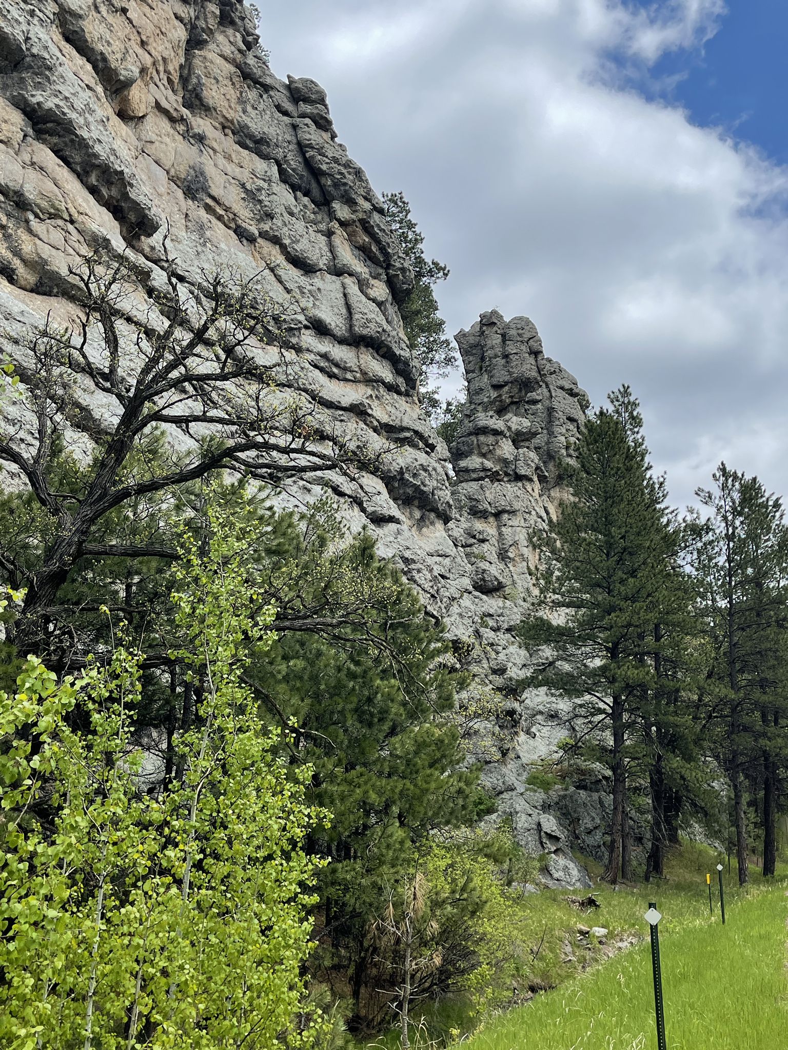 Tall, layered rock formations and green pine trees under a cloudy sky. - Keystone Historic Downtown loop from Keystone