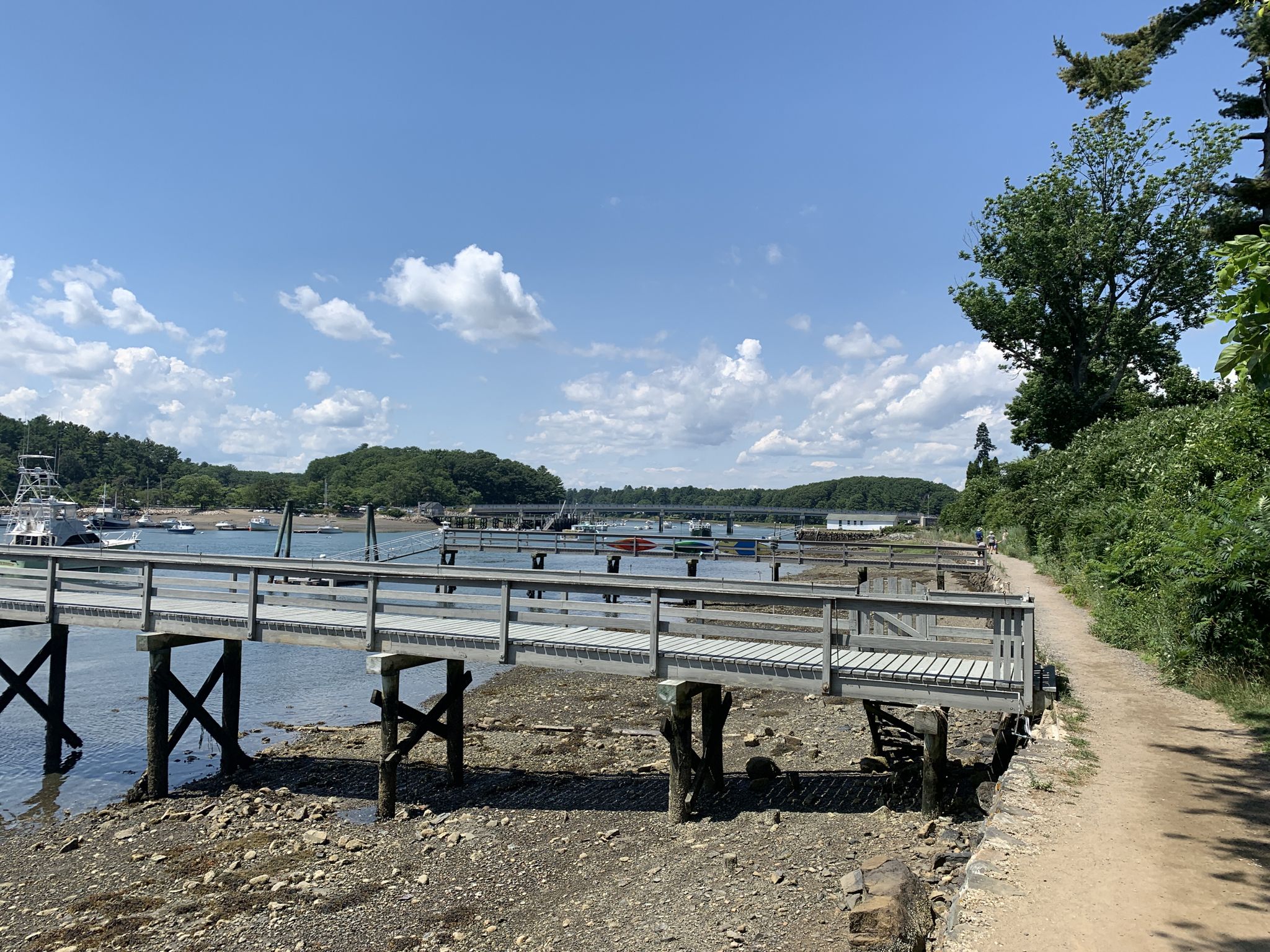 Sunny view of a long wooden pier over a rocky shoreline with boats. - Cliff Walk and Fisherman's Walk Loop