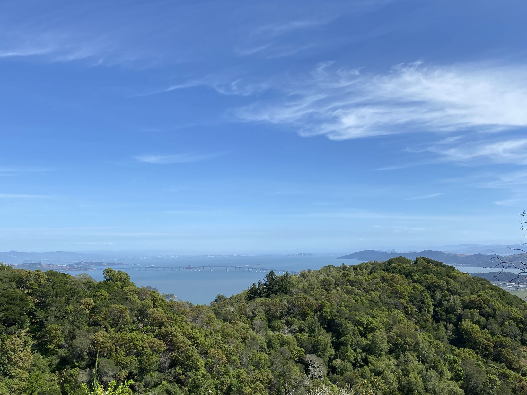 Sunny view of a water body with a distant bridge, surrounded by green hills. - Gold Hill Grade Loop