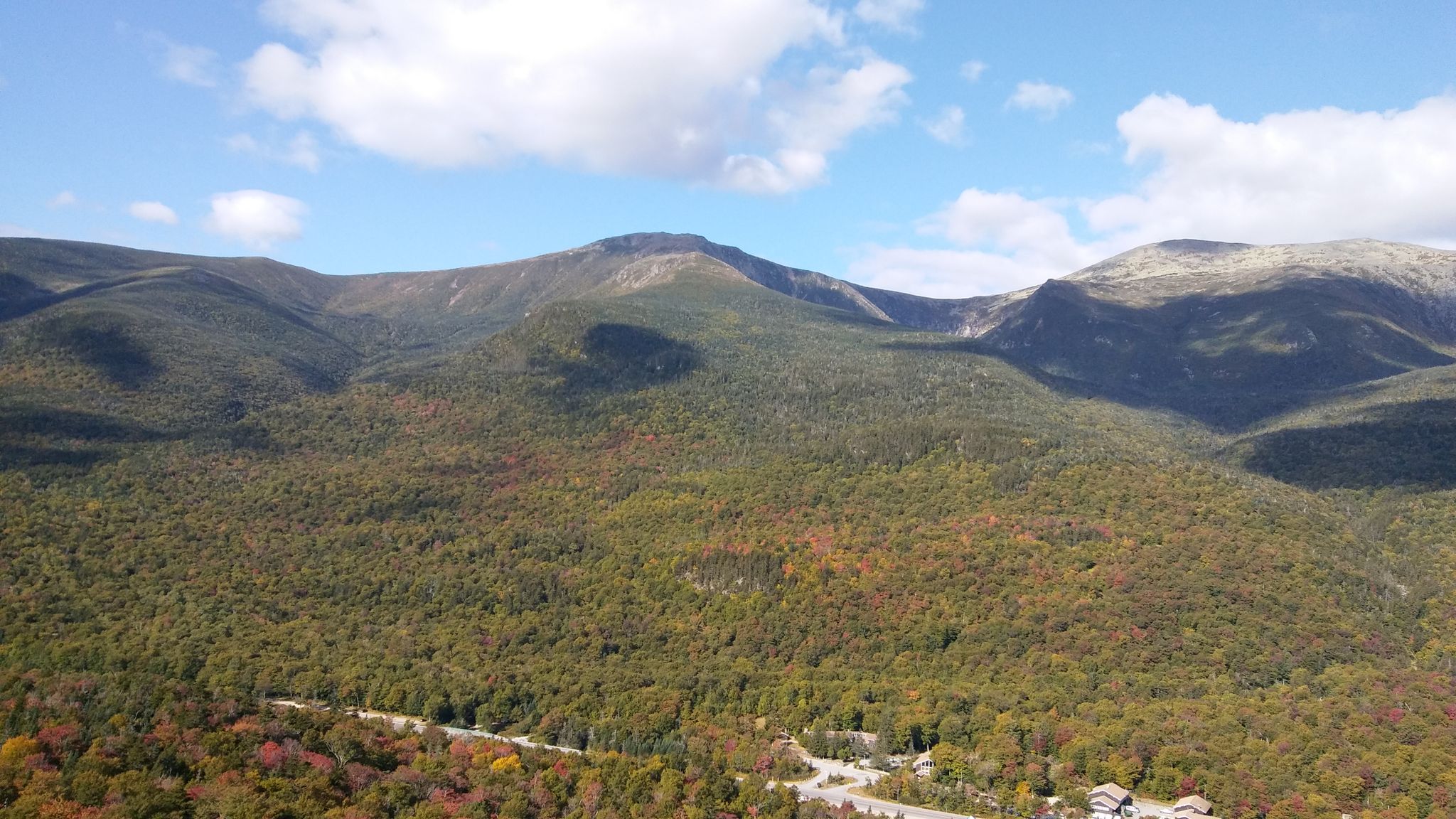 Expansive view of forested mountains with autumn colors under a blue sky. - Square Ledge Trail