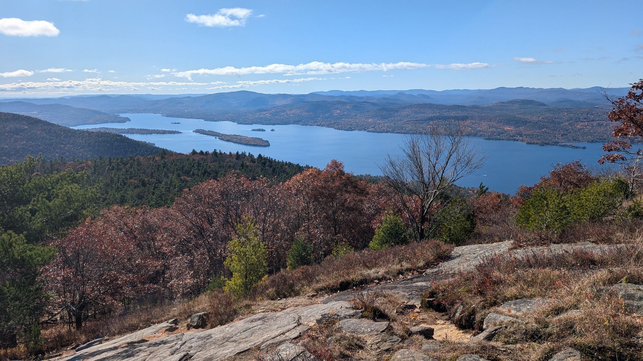 Panoramic view of a large lake surrounded by forested hills, autumn colors. - Buck Mt from Pilot Knob Trail