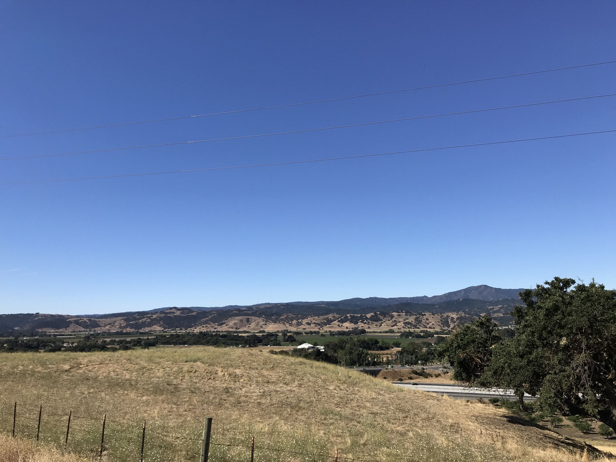 Expansive golden hills and distant mountains under a clear blue sky. - Bailey Road