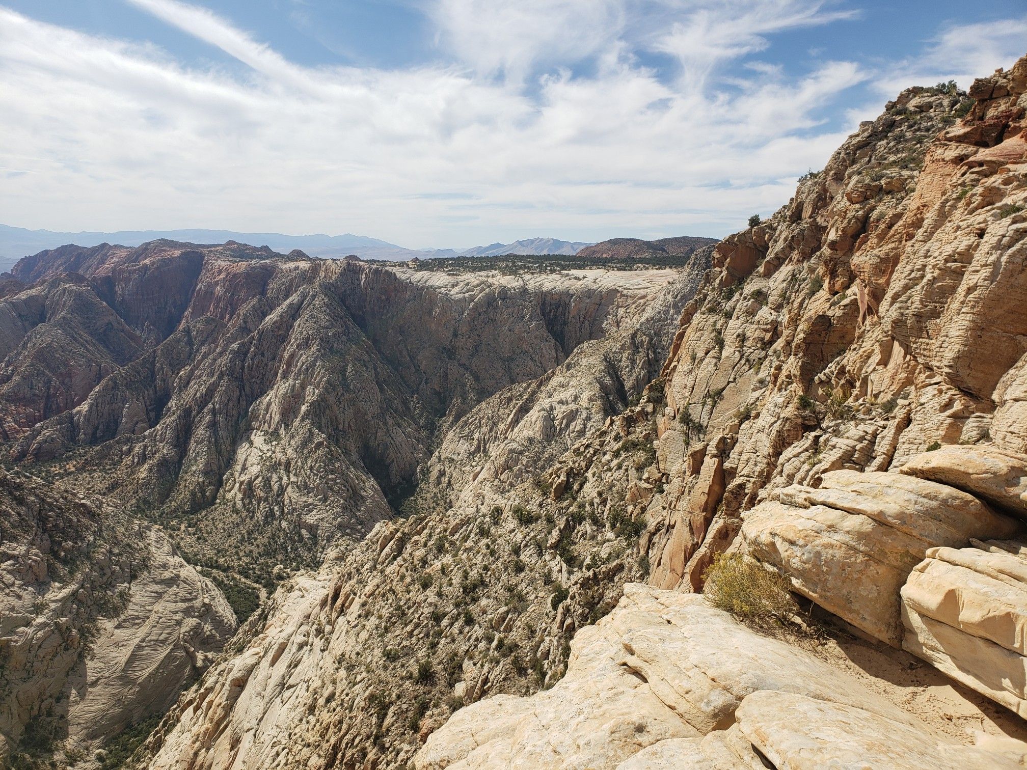 Vast canyon landscape with layered rock formations under a partly cloudy sky. - Snow Canyon Overlook Trail