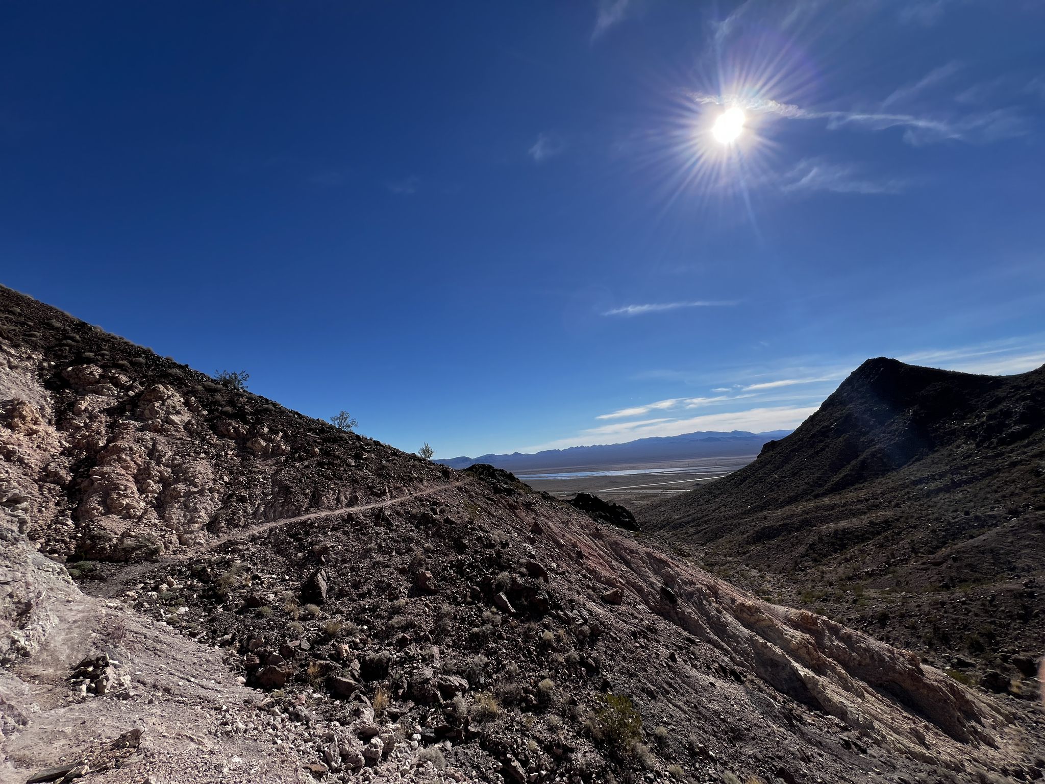 A winding trail on a steep, rocky mountain slope under a bright, sunny sky. - Old Vegas to Railroad Pass Trail