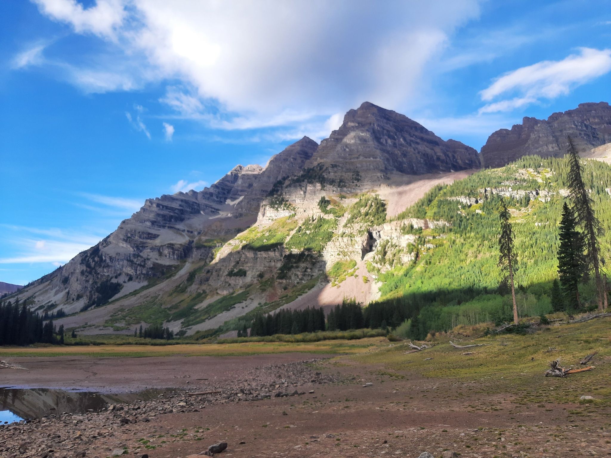 Majestic mountains with green slopes under a bright, cloudy sky. - Crater Lake