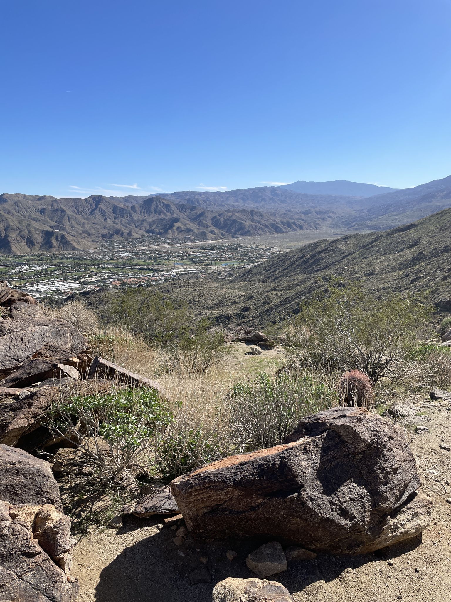 Rocky desert foreground overlooking a green valley town and distant mountains. - South Lykken Trail Loop
