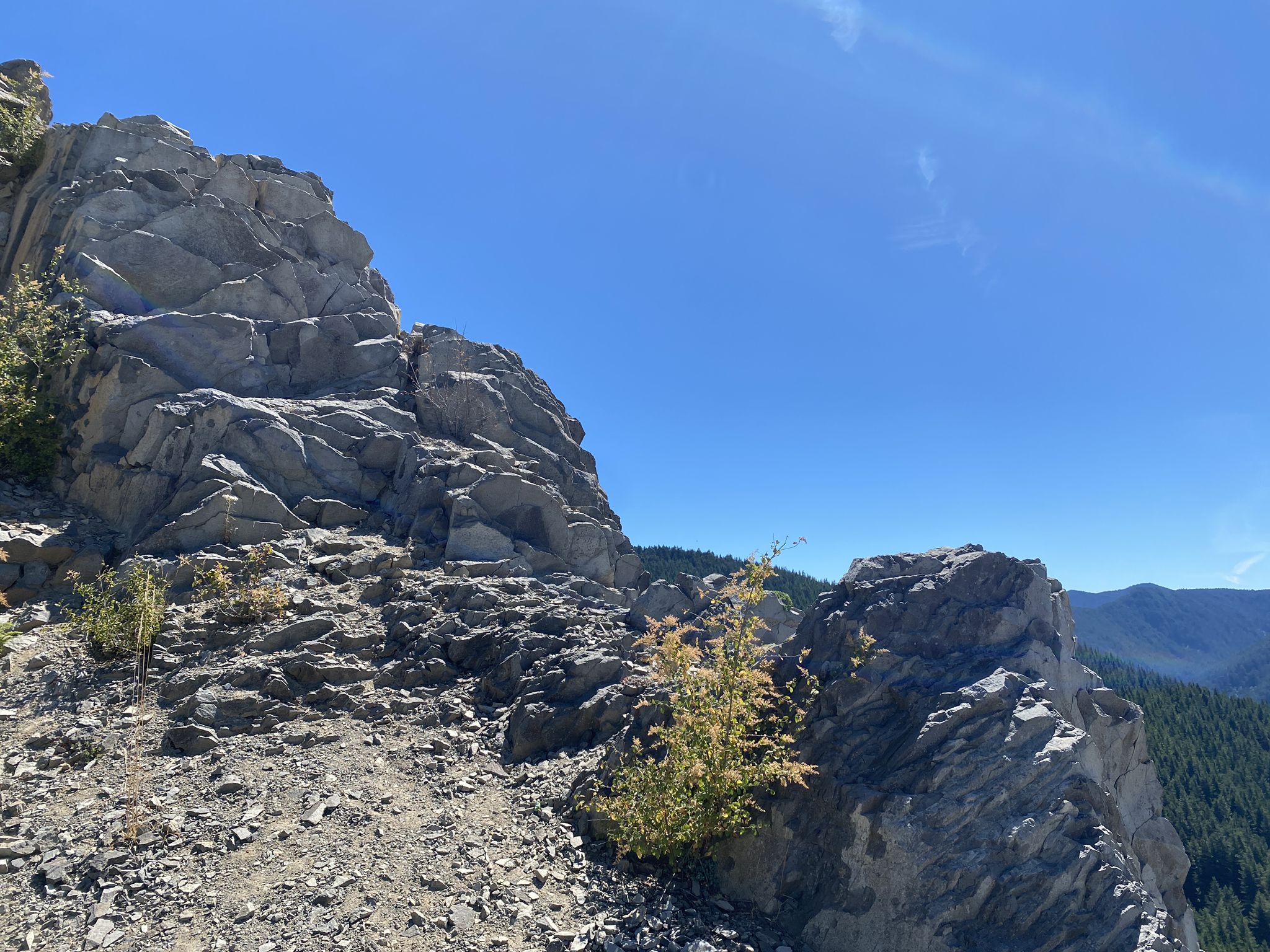 Jagged gray rock formations under a bright blue sky with distant mountains. - Douglas Trail run
