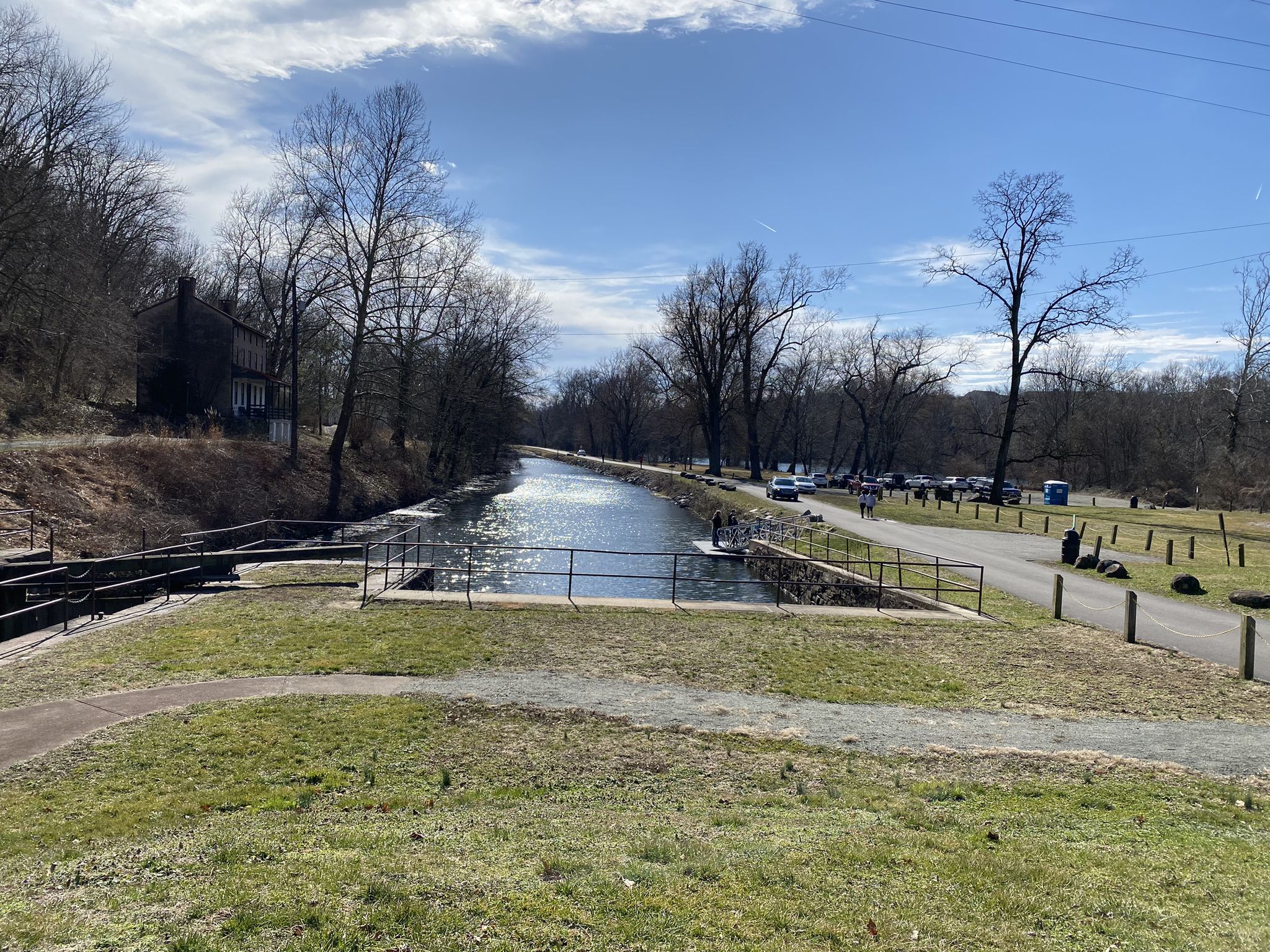 Canal with a lock, next to a paved path and bare trees under a blue sky. - Lock 60 loop from Phoenixville