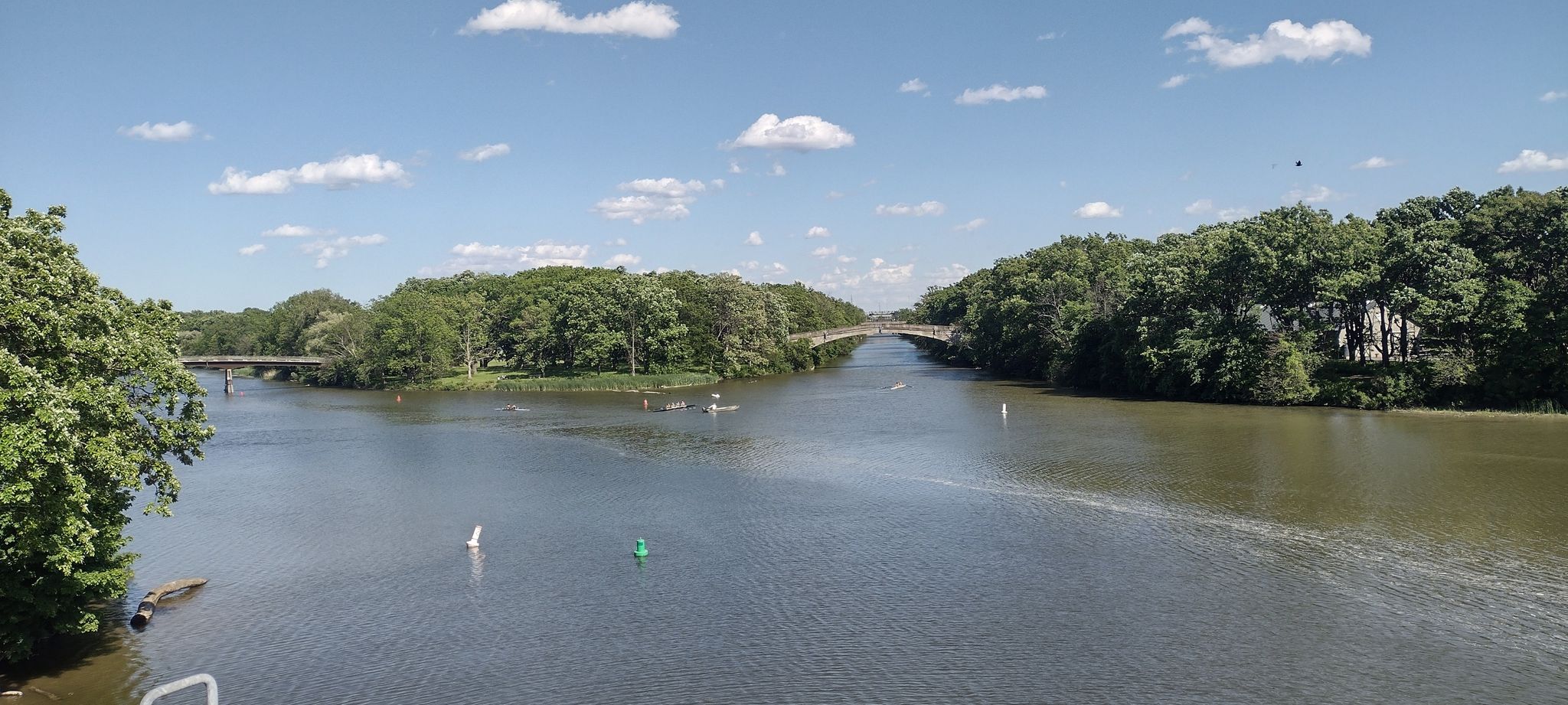 Wide river with distant bridges, green trees, and a bright, partly cloudy sky. - Erie Canal Trail – Eerie Canal Gravel section loop from Rochester